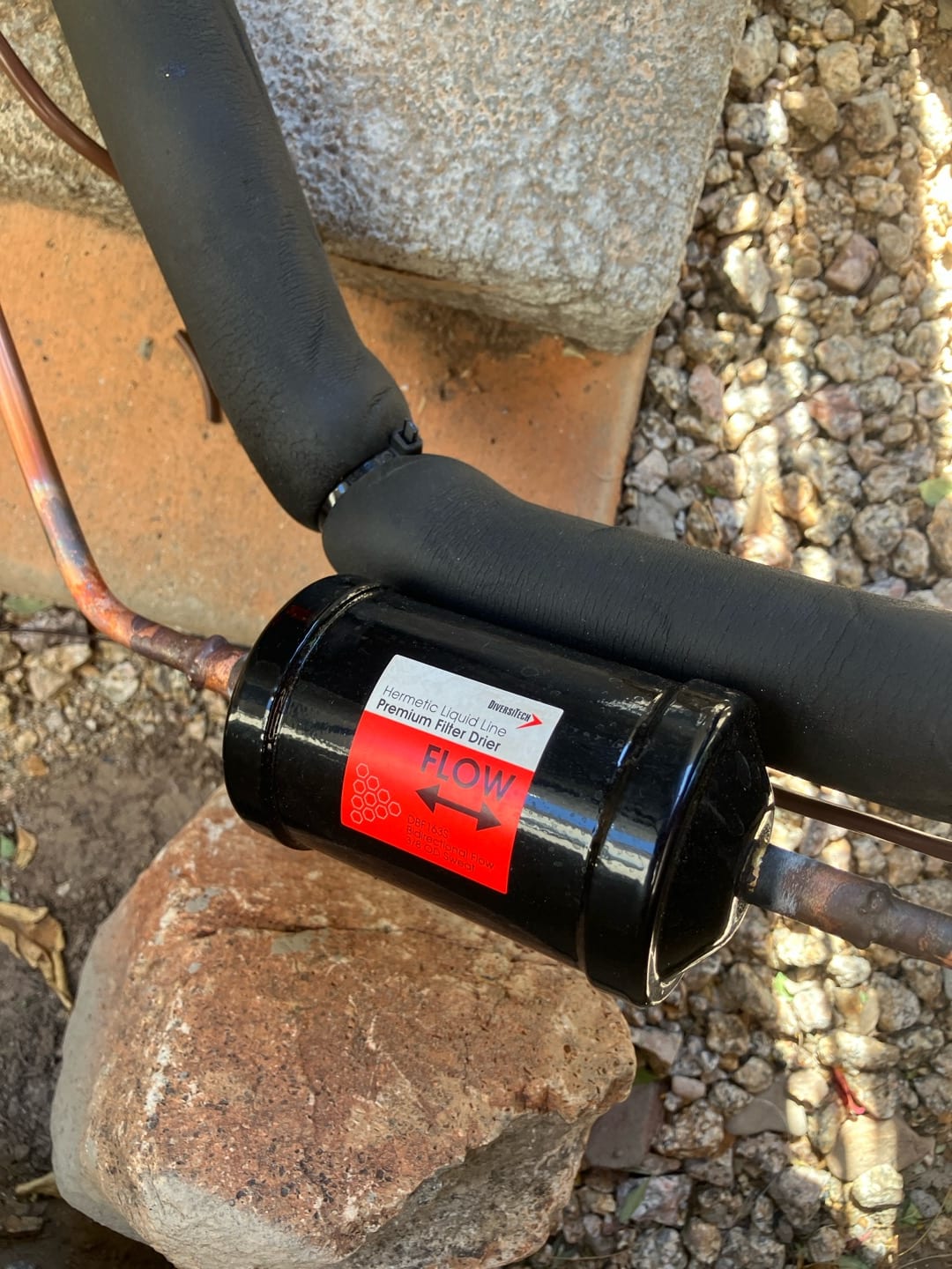 New liquid-line filter drier installed in the refrigerant circuit with insulated line set and proper flow direction indicated.