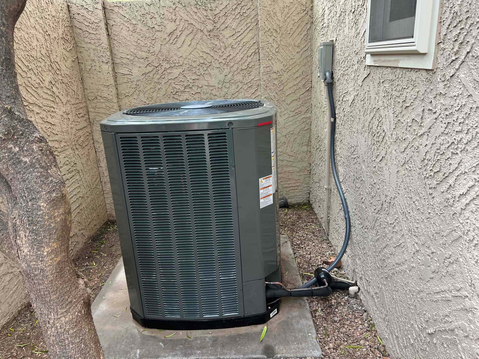 New outdoor condenser set on a level pad with insulated refrigerant lines, electrical disconnect, and sealed wall penetration.