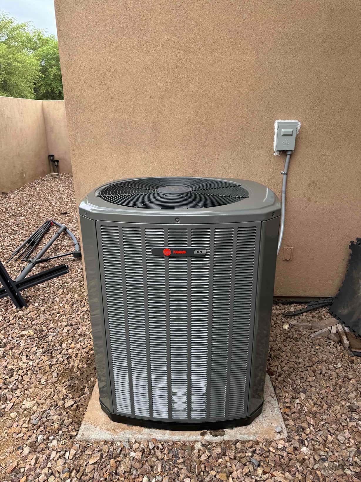 New outdoor condenser set on a level pad with sealed wall penetration and weatherproof disconnect installed beside the unit.
