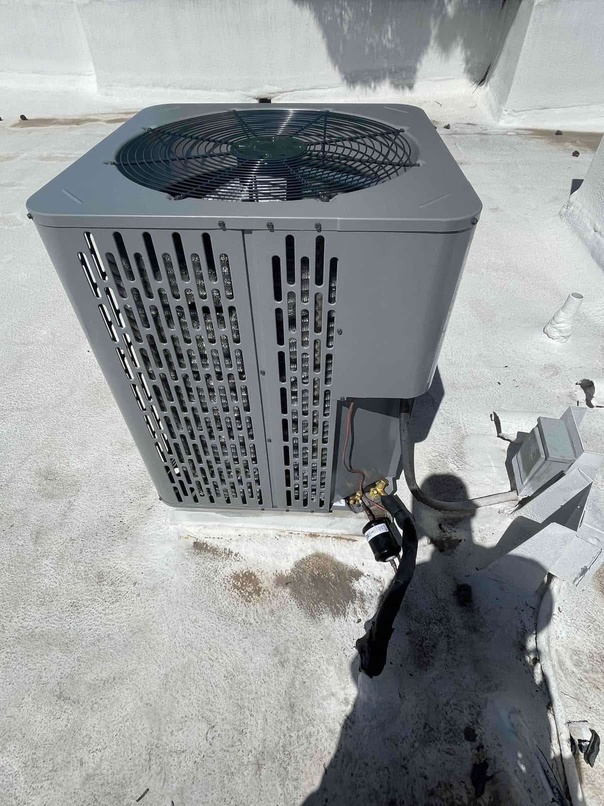 New outdoor condenser set on a roof surface with insulated line set connected and service valves accessible.