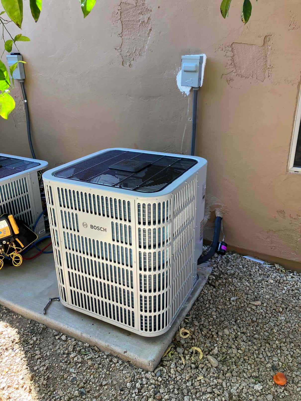 New outdoor condenser units set on level pads with insulated refrigerant lines and weatherproof electrical disconnects mounted on the wall.