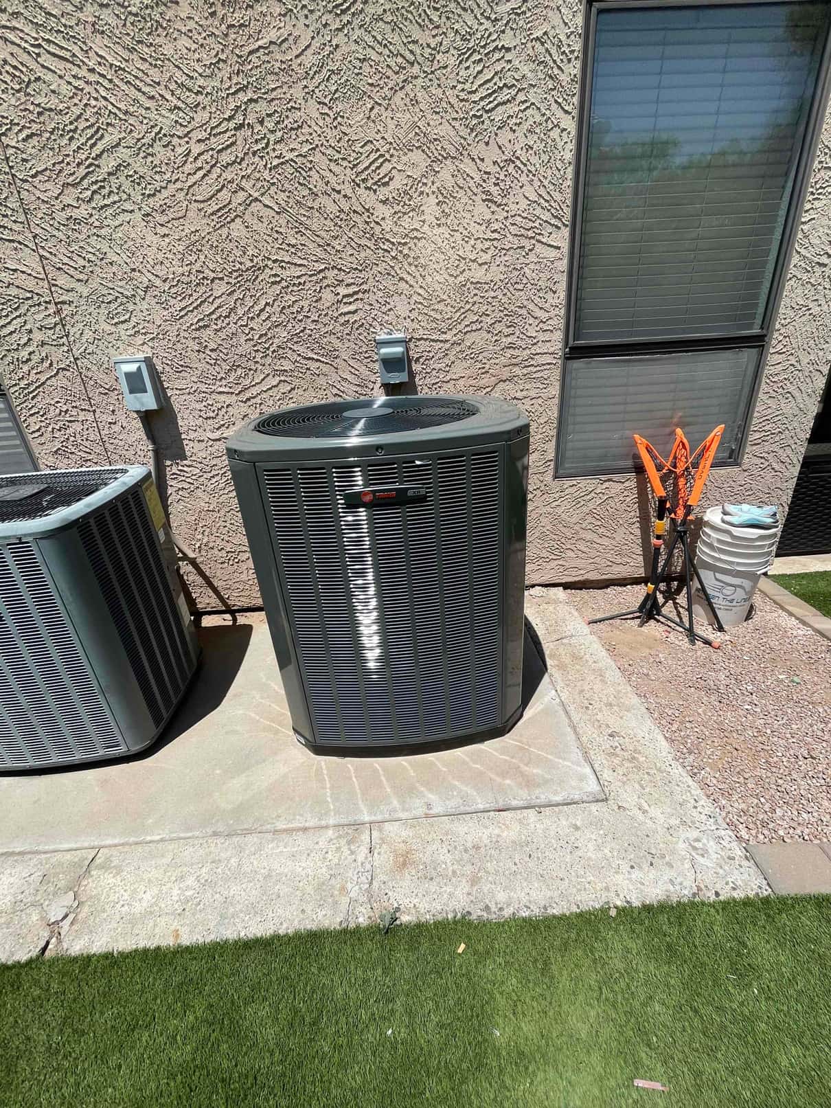 New outdoor heat pump condenser set on a level pad with nearby disconnects and insulated line set routed to the wall.