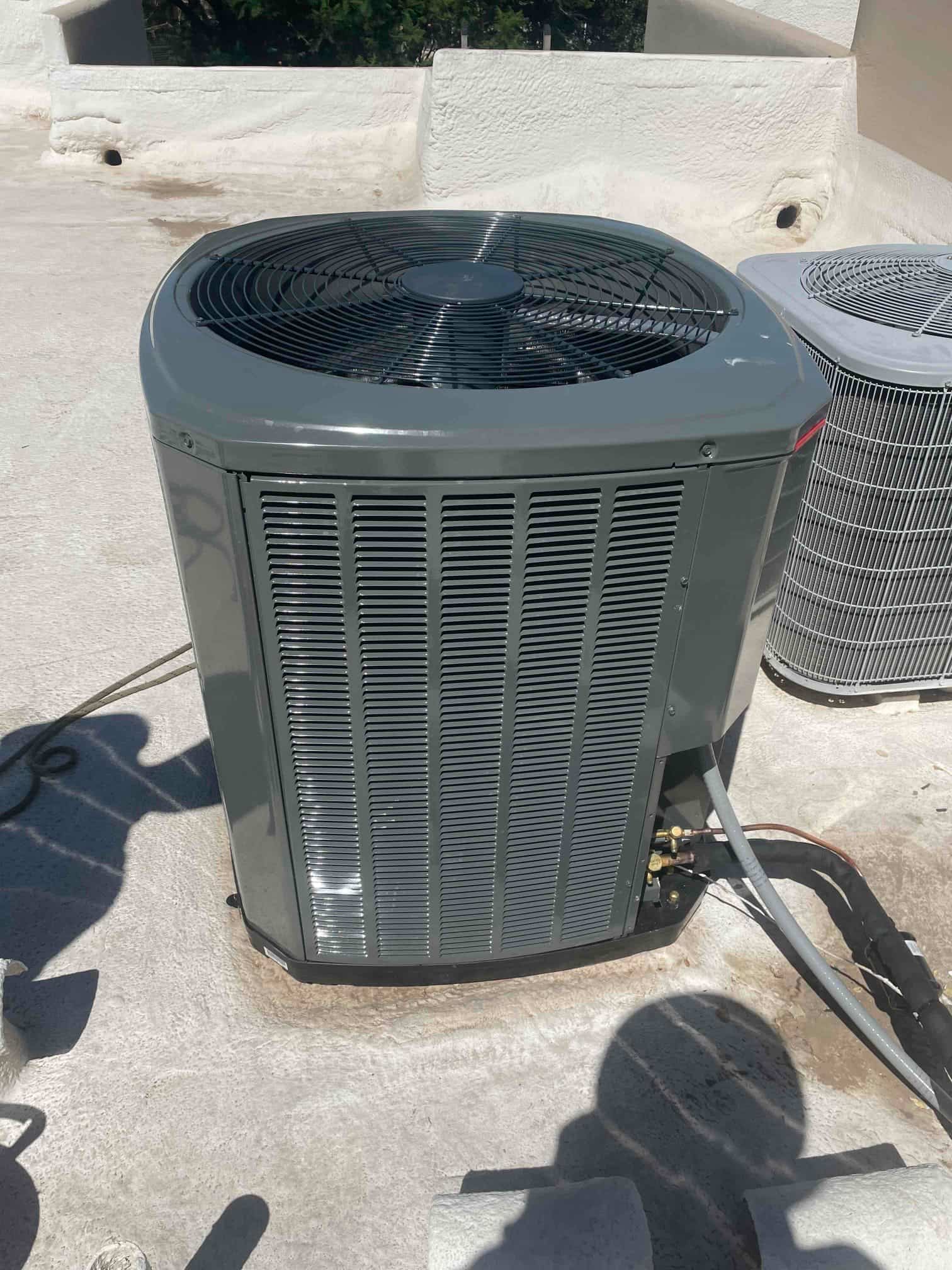 New outdoor heat pump condenser set on a rooftop pad with insulated refrigerant lines and service valves accessible.