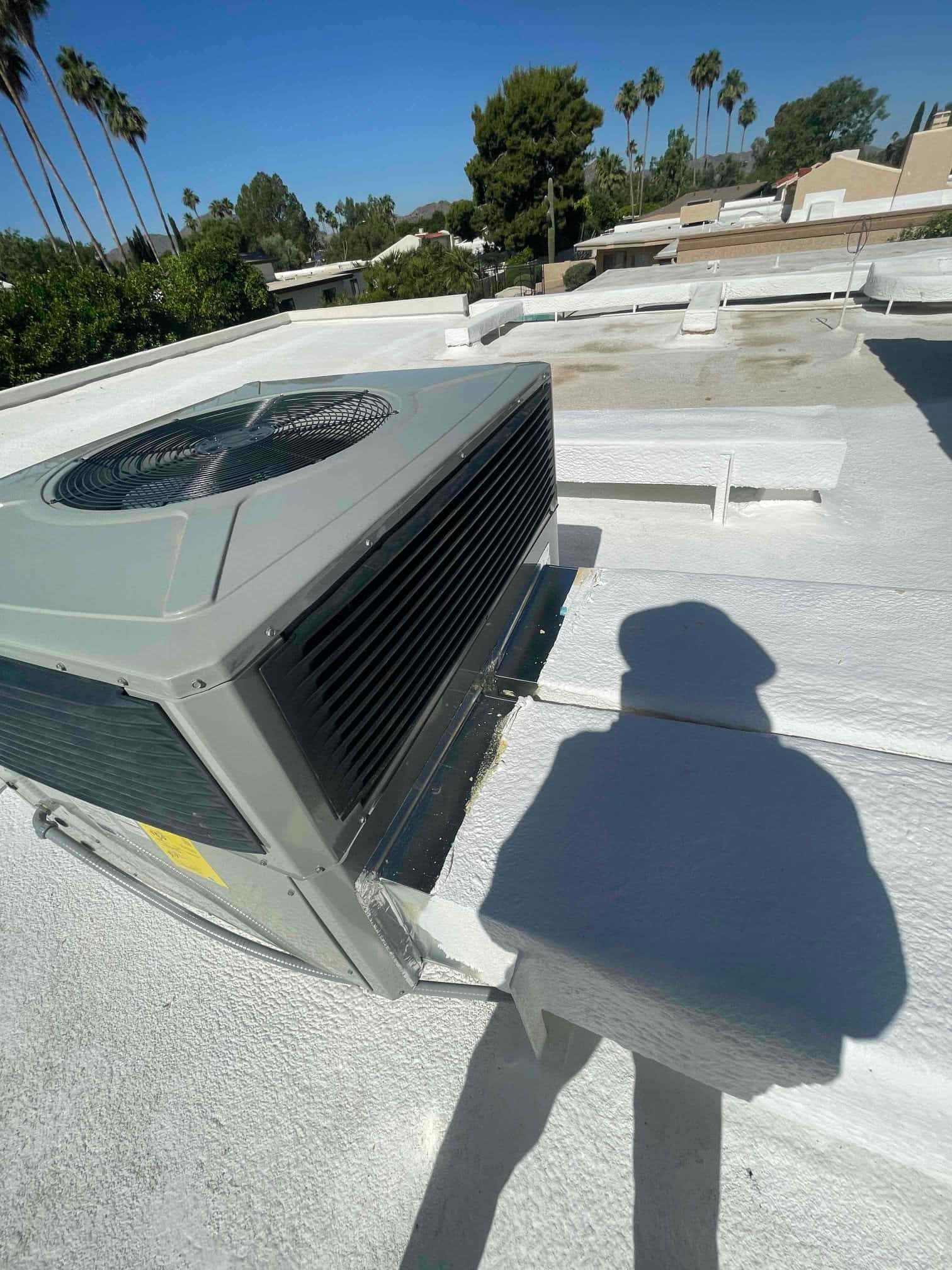 New rooftop condenser set on a coated flat roof curb with secured electrical whip and level mounting.