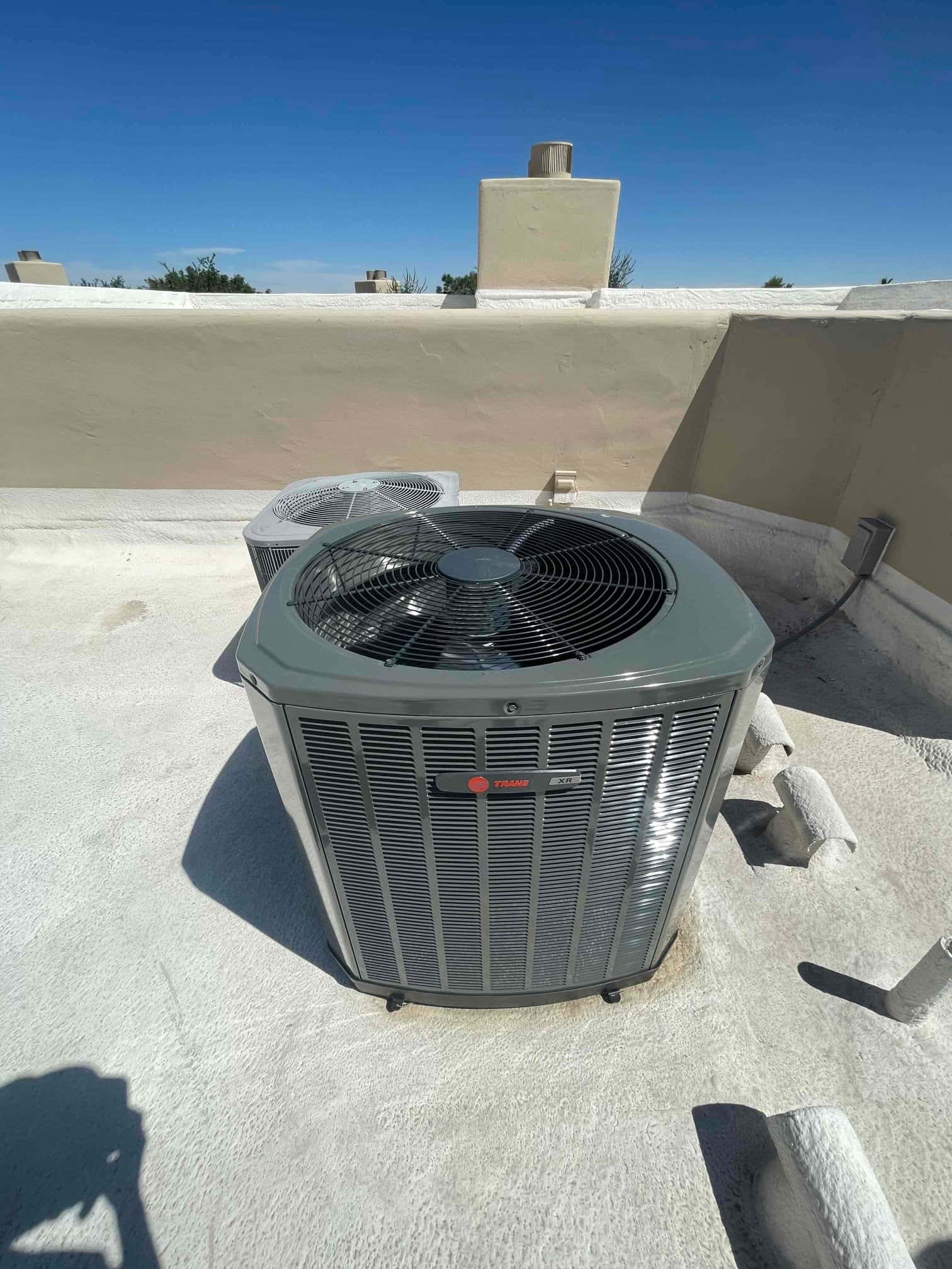 New rooftop heat pump condenser installed on coated roof with electrical whip and insulated line set penetrations nearby.