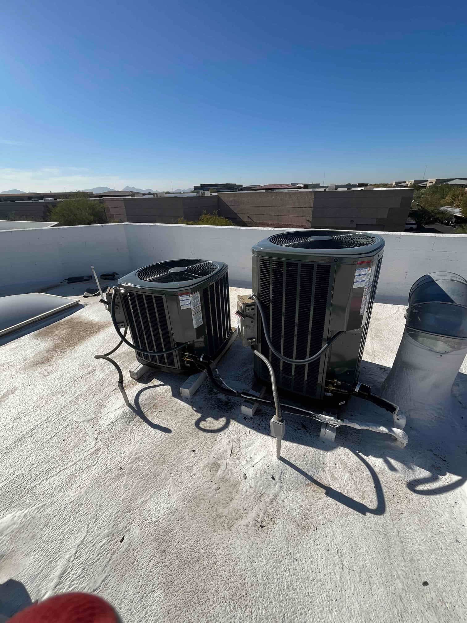 Two new rooftop heat pump condensers set on elevated pads with insulated line sets and weatherproof electrical whip connections.