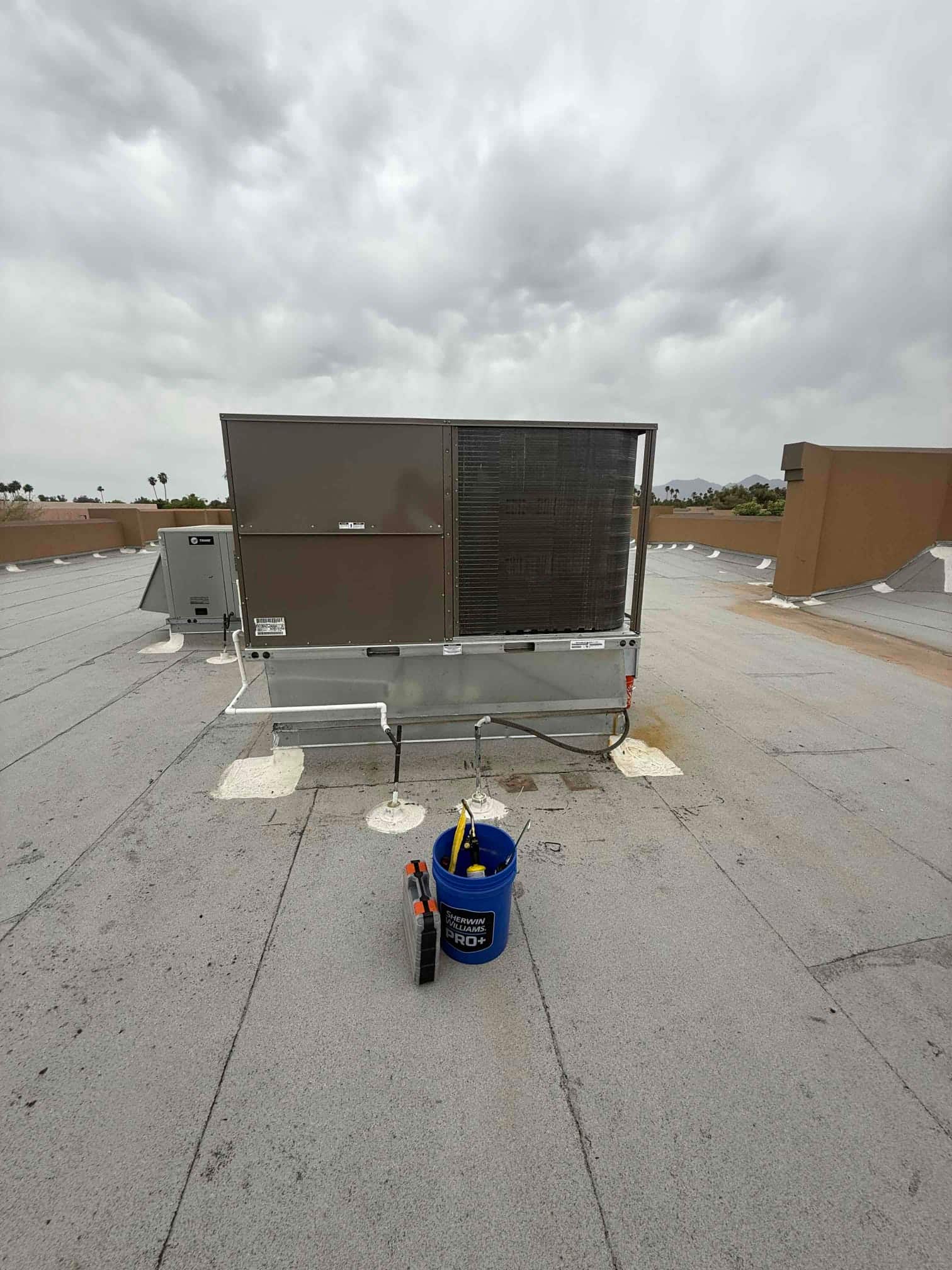 New rooftop package HVAC unit installed on curbs with insulated refrigerant piping and rooftop disconnect visible nearby.