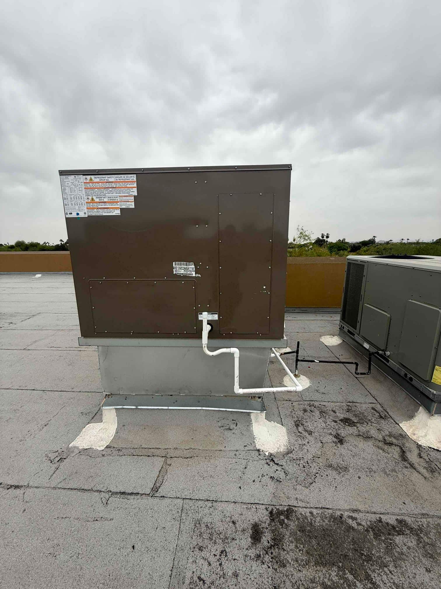 New rooftop package unit set on a curb with insulated condensate drain piping routed and sealed roof penetration.