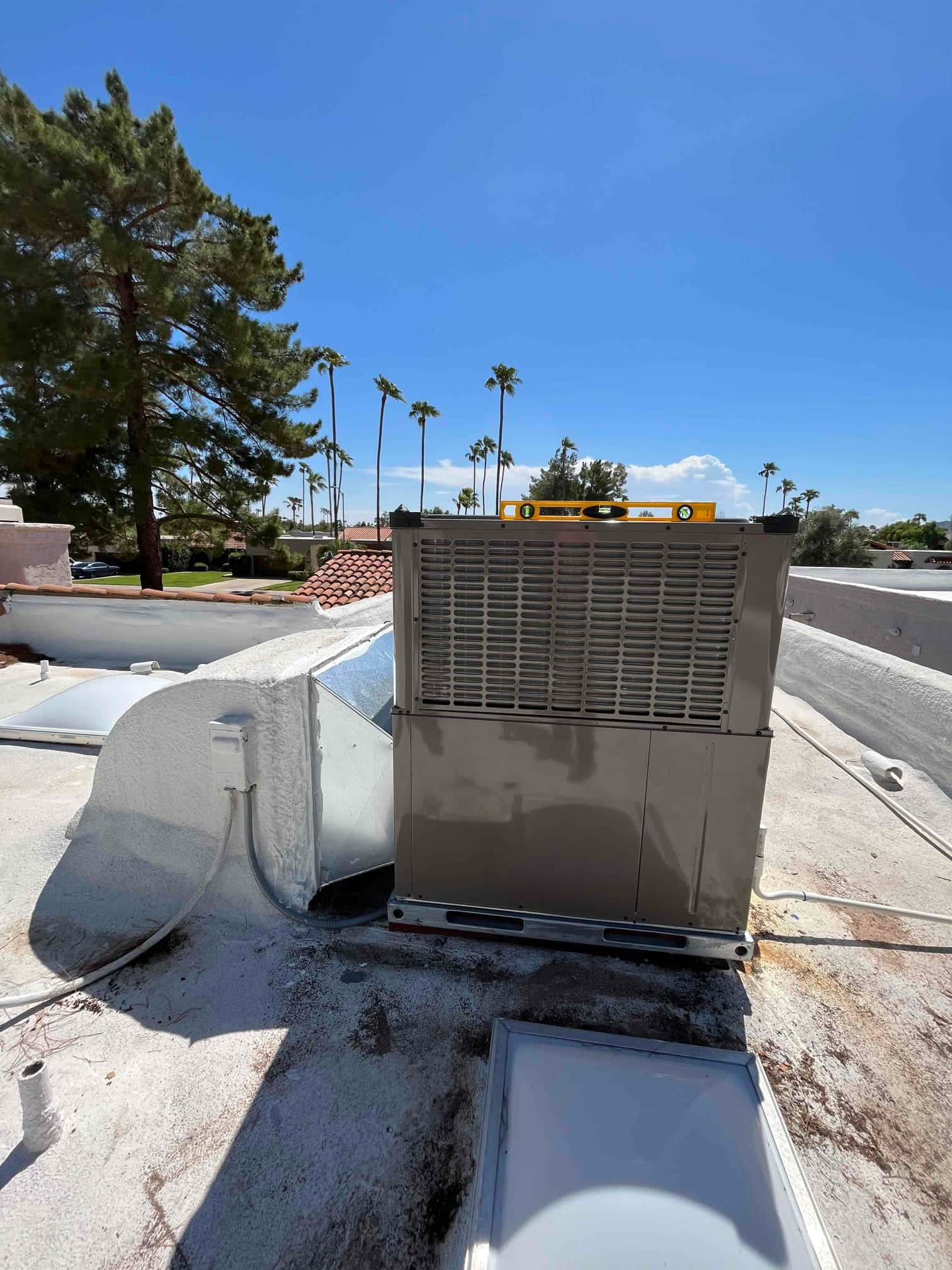 New rooftop package unit set on a level curb with sealed duct connection and installed electrical disconnect nearby.