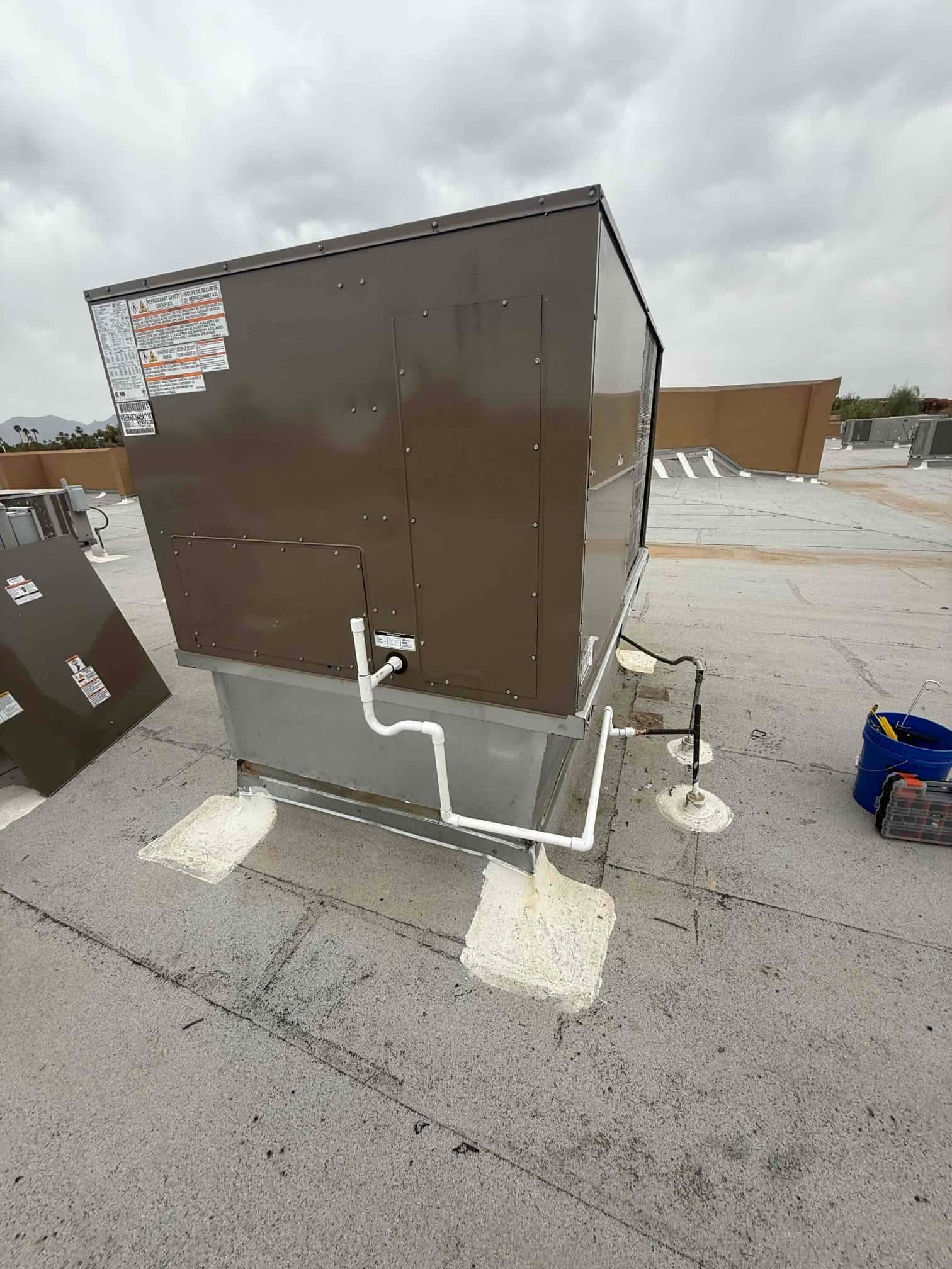 New rooftop packaged HVAC unit installed on curb with sealed condensate drain piping and rooftop penetrations properly flashed.