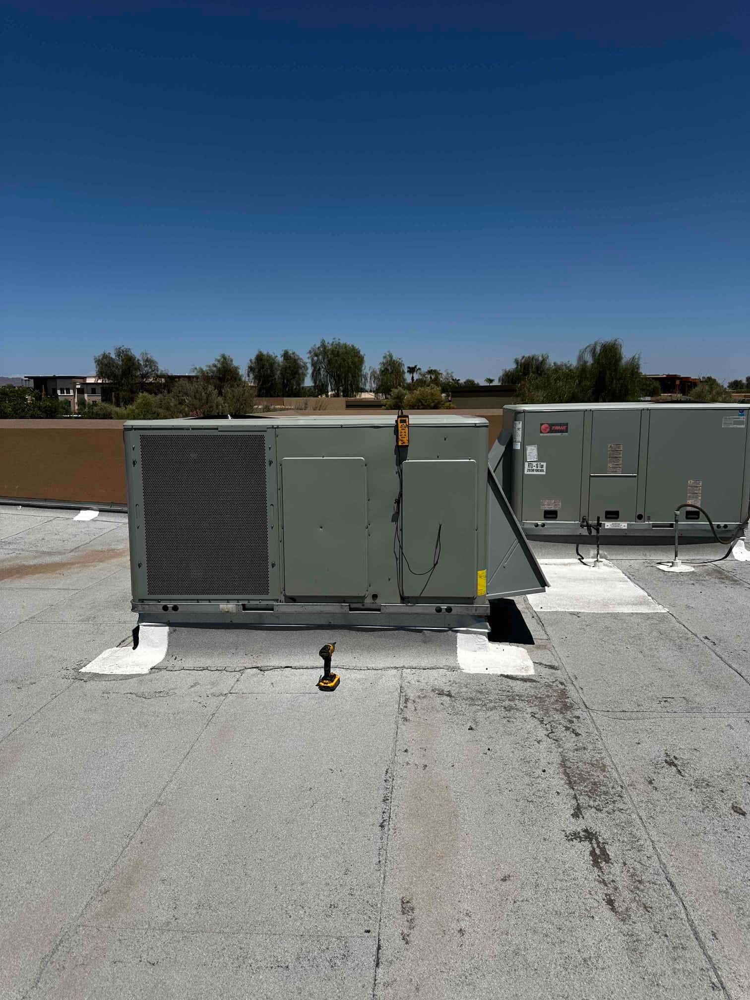 New rooftop packaged HVAC unit set in place on curb with sealed roof penetrations and tools visible during installation.