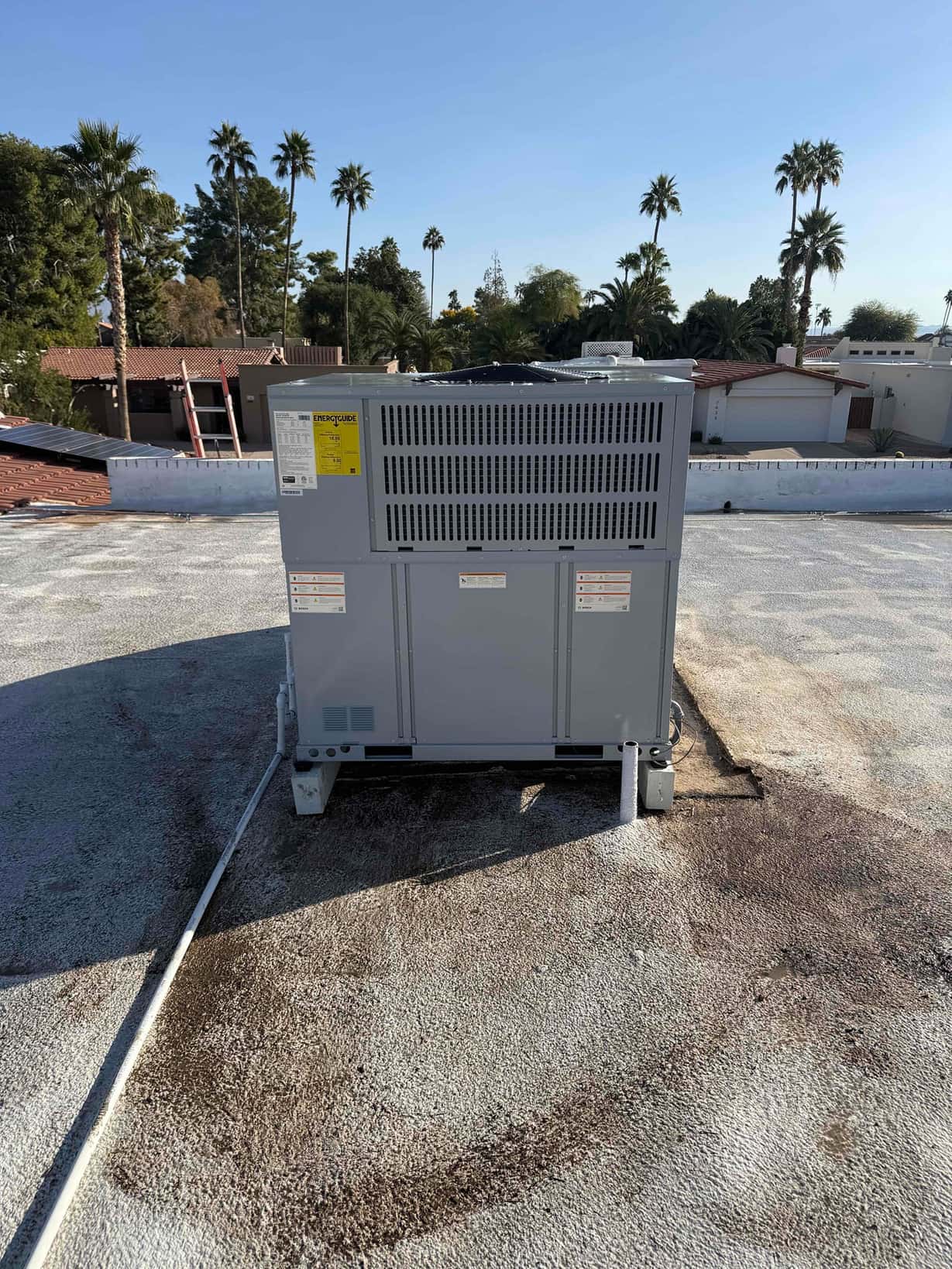 New rooftop packaged HVAC unit set on support stands with sealed roof penetration and electrical conduit routed along the surface.