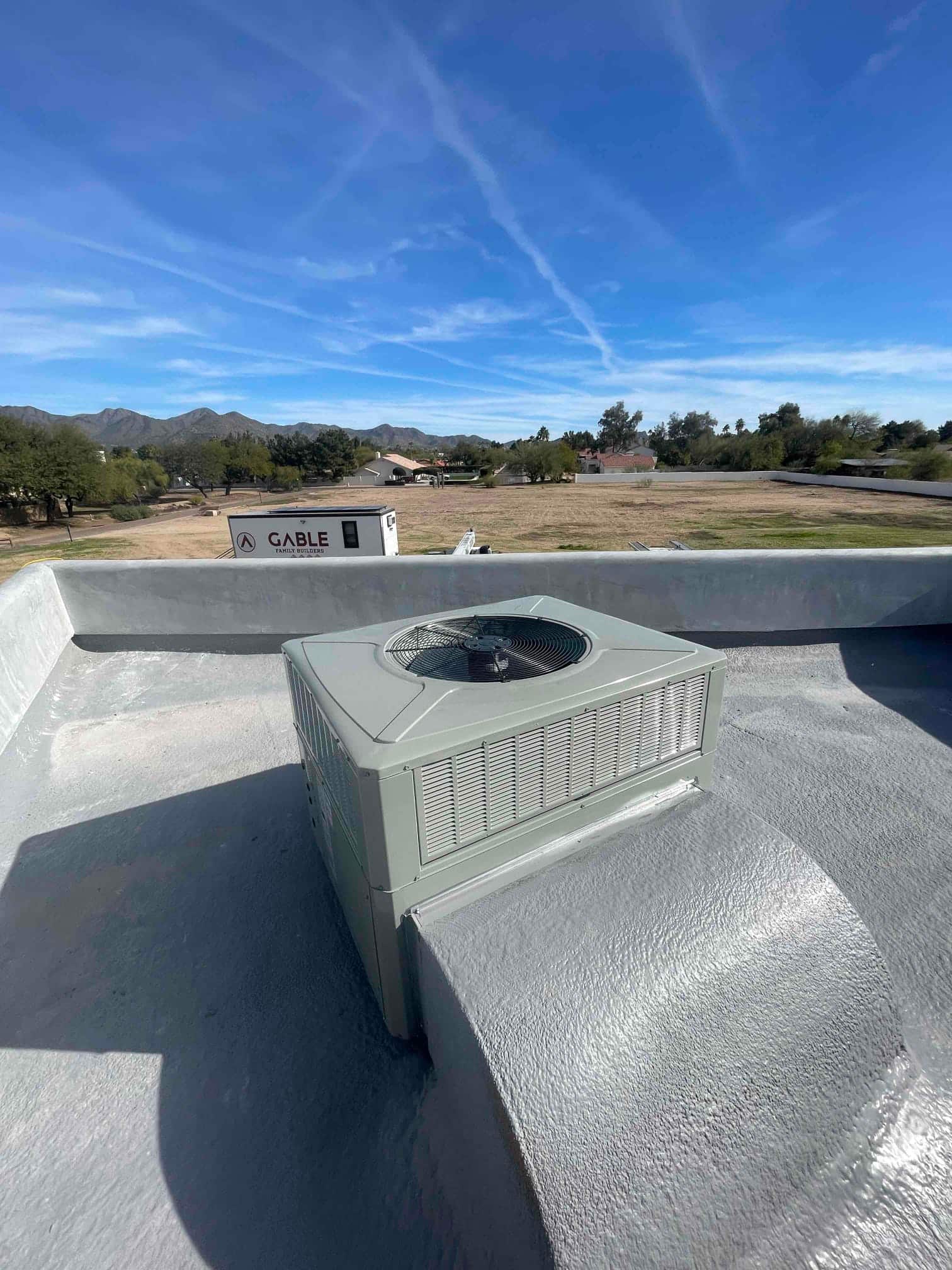 New rooftop packaged unit installed on a sealed curb, with condenser fan and cabinet visible against a clear sky.