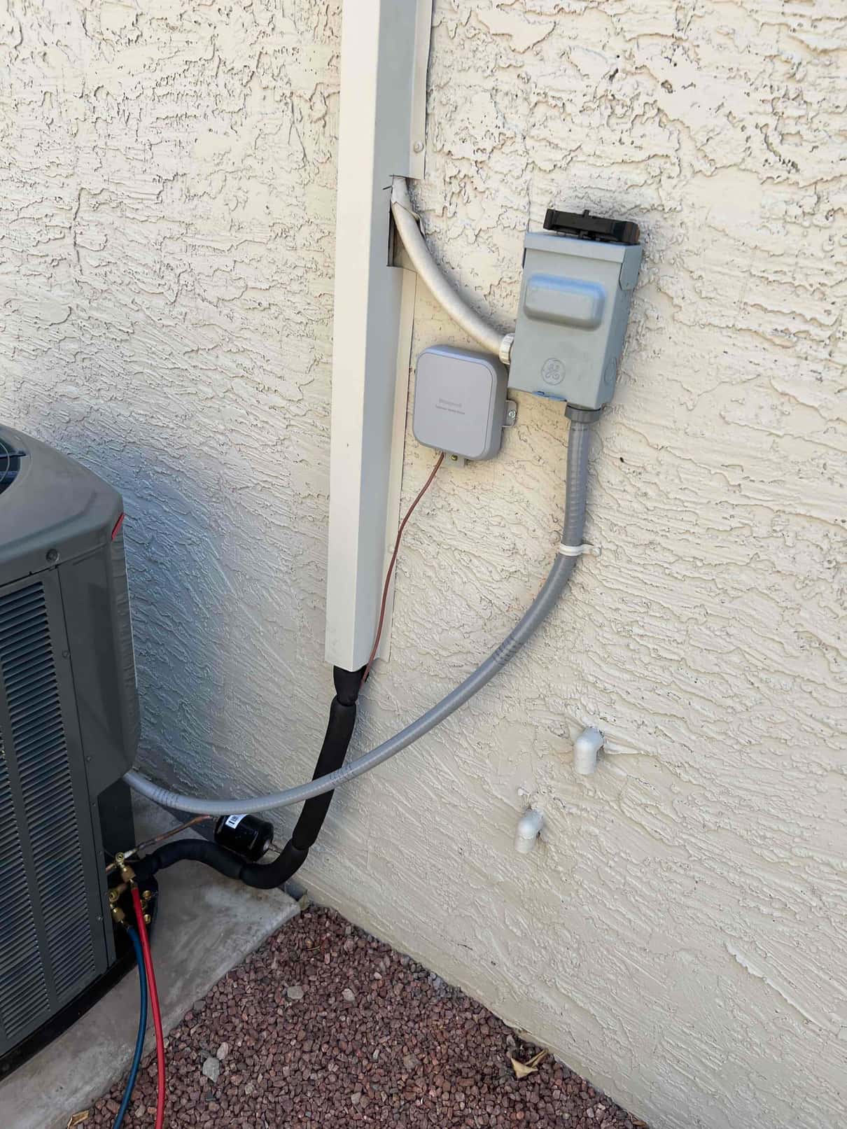 Outdoor condenser connected with insulated line set, electrical disconnect, flexible conduit, and sealed wall penetrations at the installation site.
