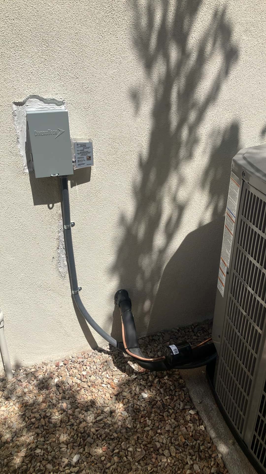 Outdoor condenser next to newly installed weatherproof disconnect, flexible conduit, and insulated refrigerant line set with filter drier.