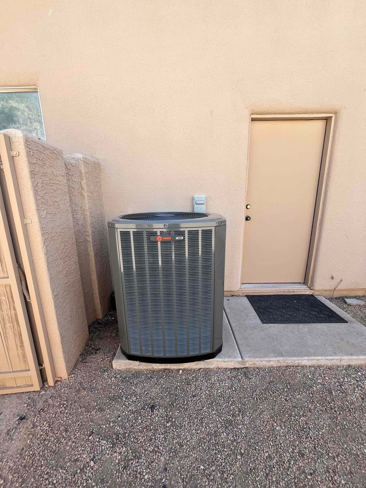 Outdoor condenser set on a level pad beside the building, with nearby disconnect and clear service access around the unit.