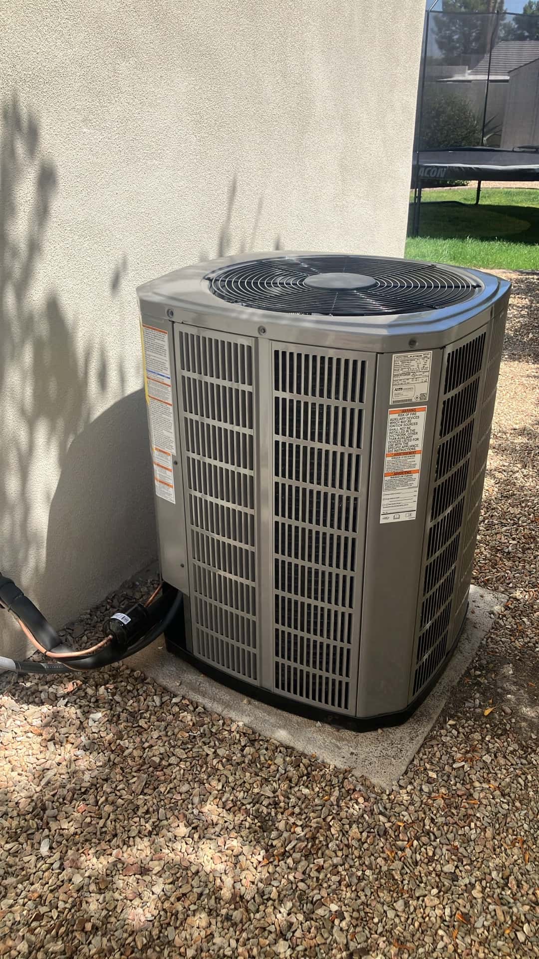 Outdoor condenser unit set on a level pad with insulated line set and sealed wall penetration at the installation site.