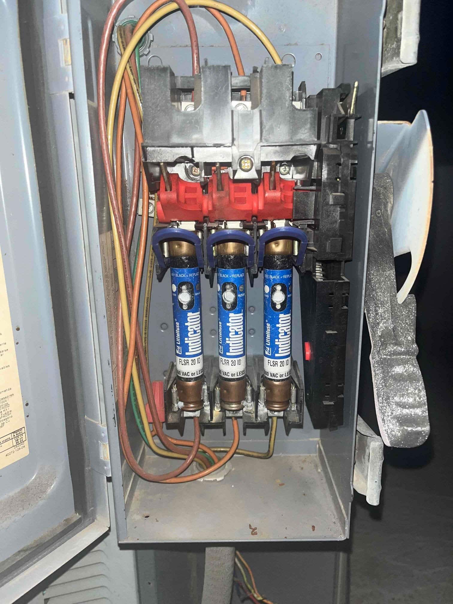 Outdoor disconnect enclosure with three cartridge fuses installed and line and load conductors routed through the cabinet.