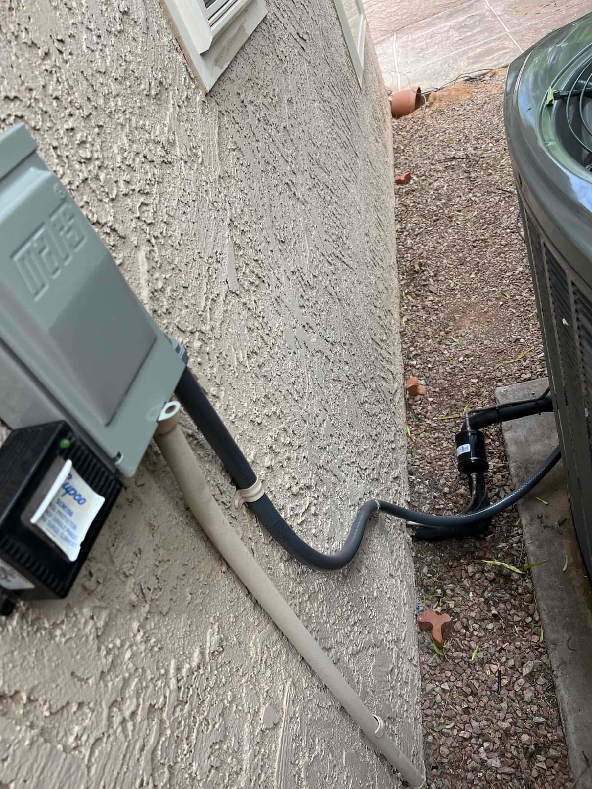 Outdoor disconnect, insulated refrigerant lines, and line set filter-drier connected to the new condenser beside the exterior wall.