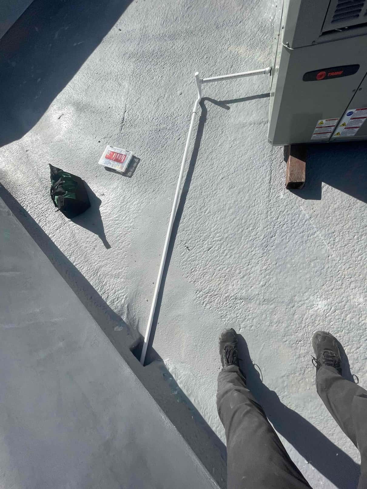 Outdoor heat pump set on roof with newly routed and painted line set entering a sealed roof penetration.
