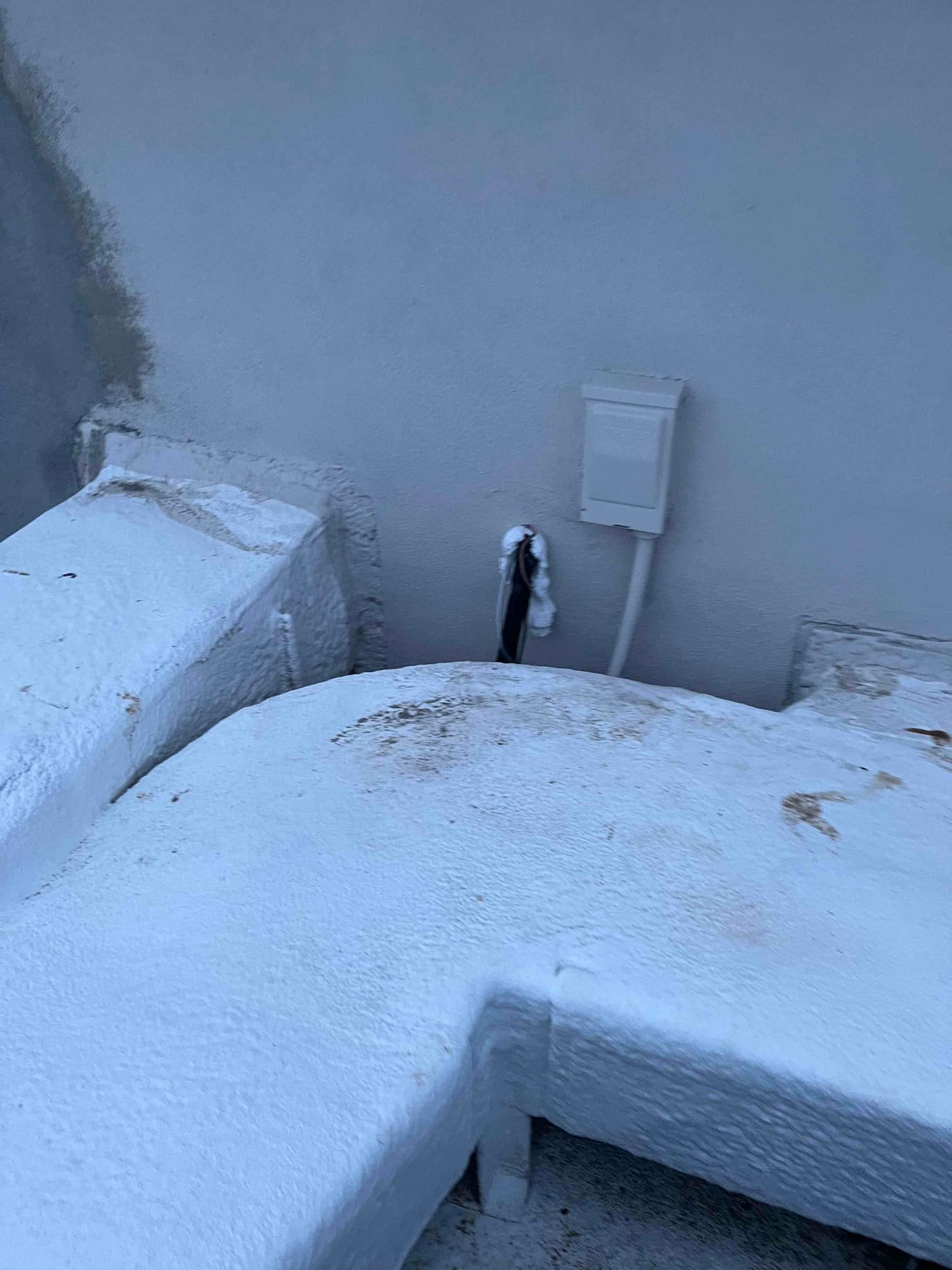 Outdoor wall penetration with sealed line set and mounted weatherproof electrical disconnect near newly installed mini-split location.