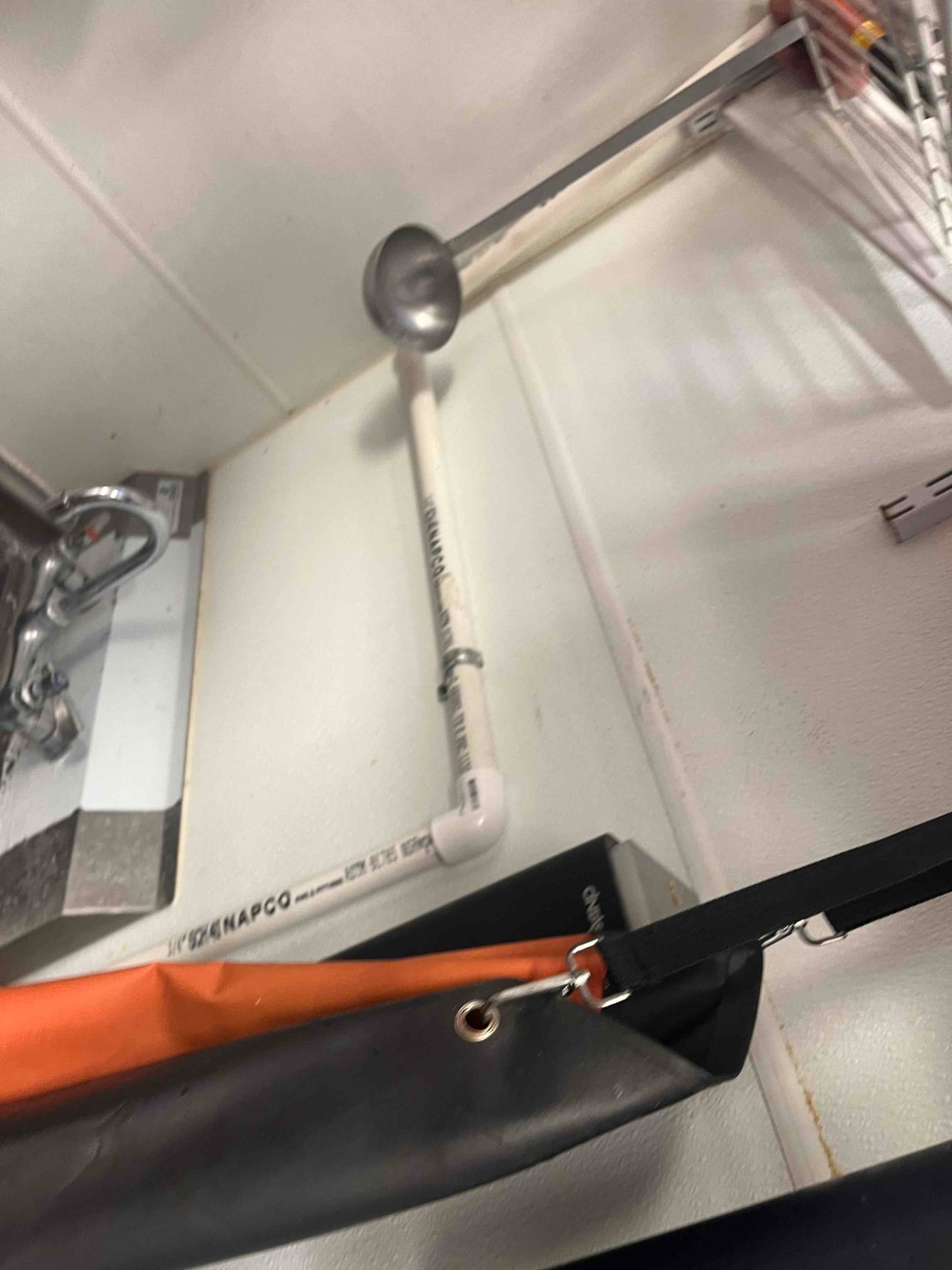 PVC condensate drain with elbow fitting routed along the wall near the indoor unit, showing clean installation and proper slope.