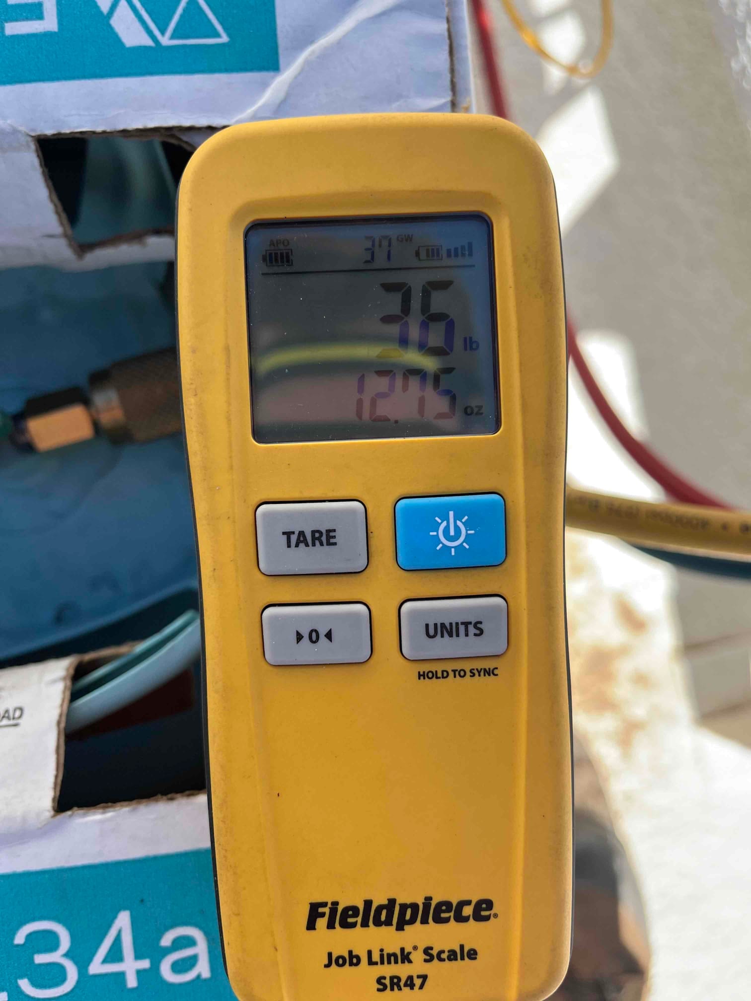 Refrigerant charging scale display shows 3.6 pounds and 12.75 ounces during system charging at the outdoor unit.