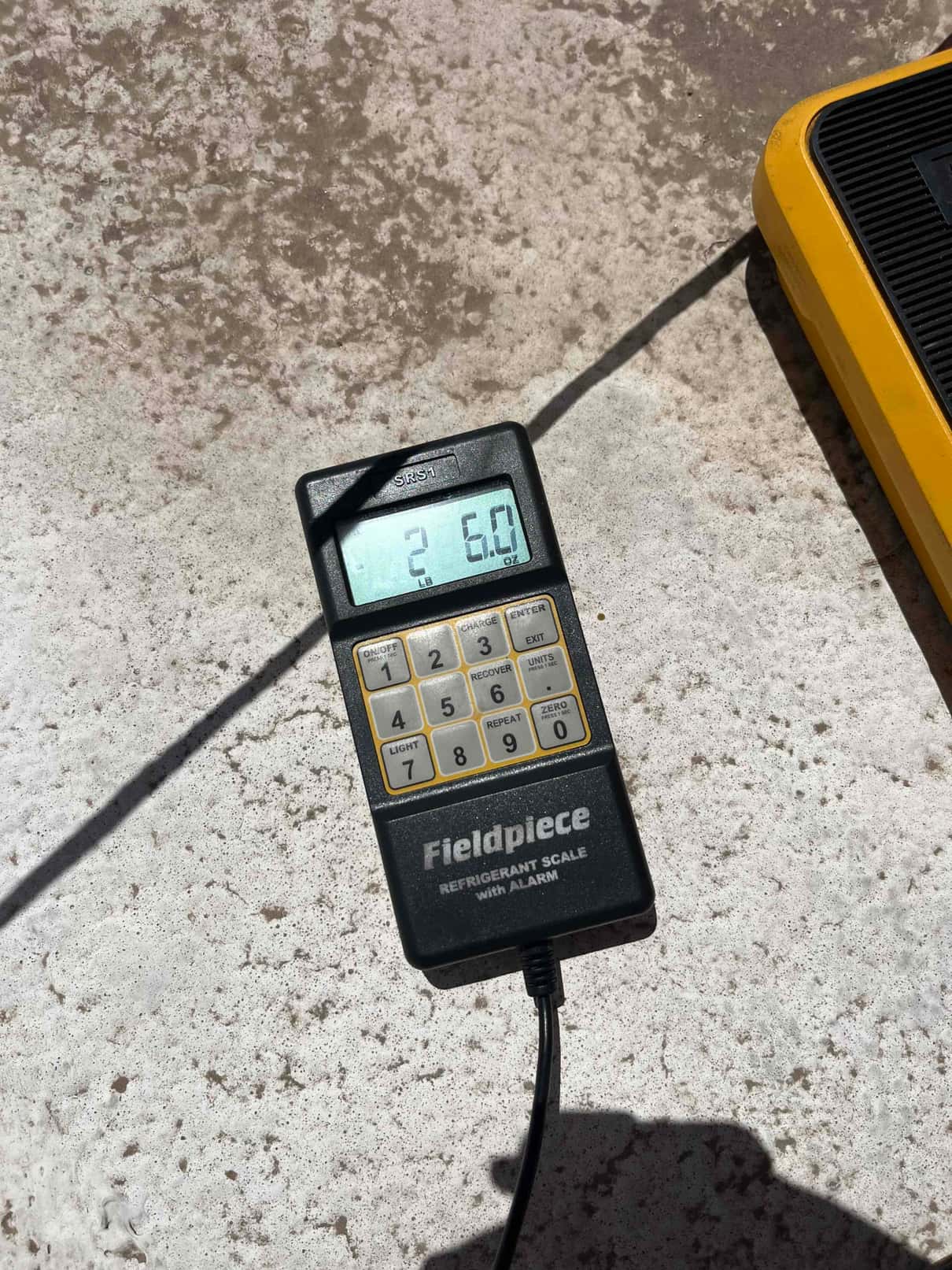 Refrigerant charging scale display shows 5.0 lb of refrigerant during R-410A recharge work.