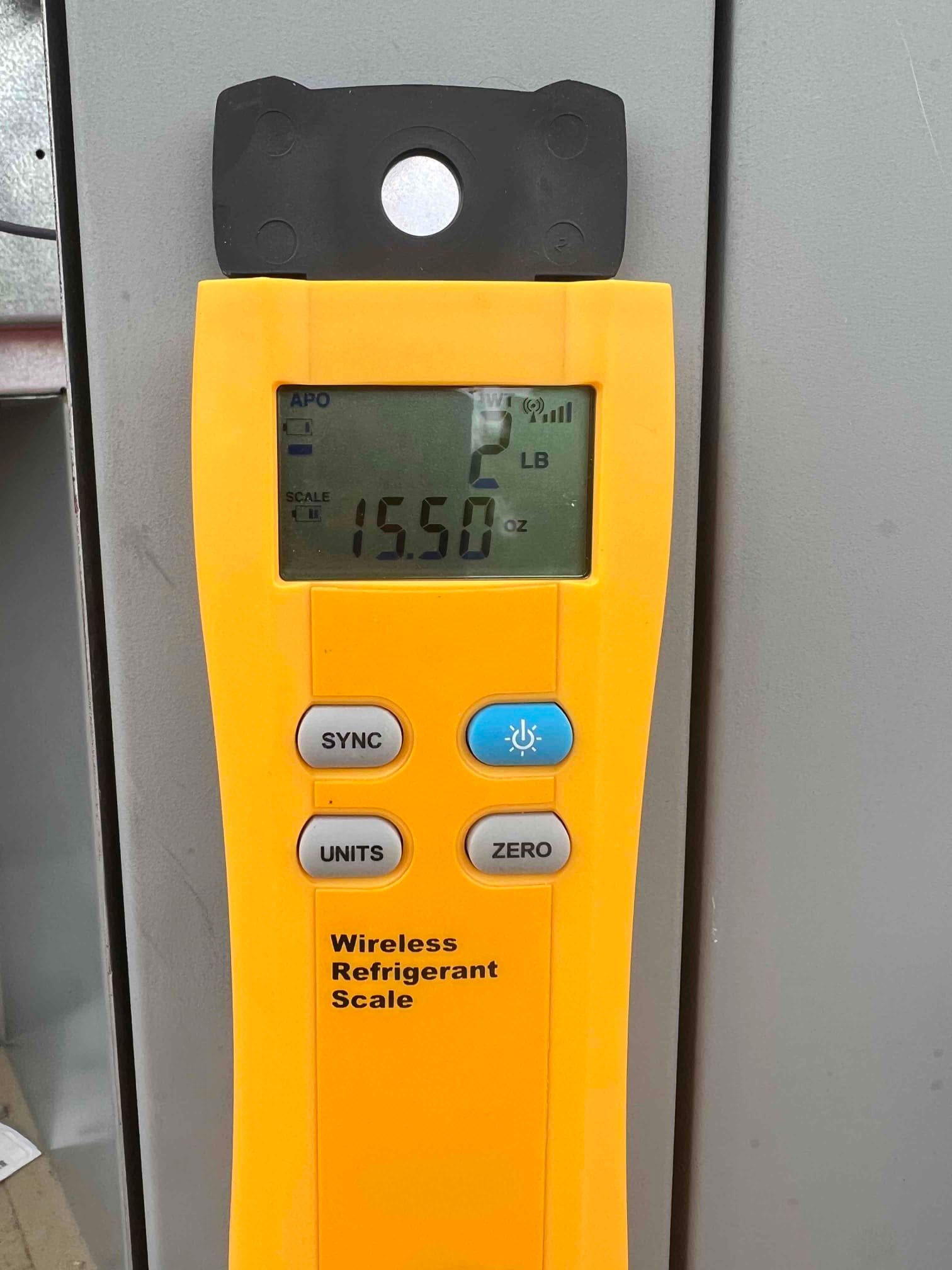 Refrigerant scale photographed during the service visit; no numerical reading is transcribed.