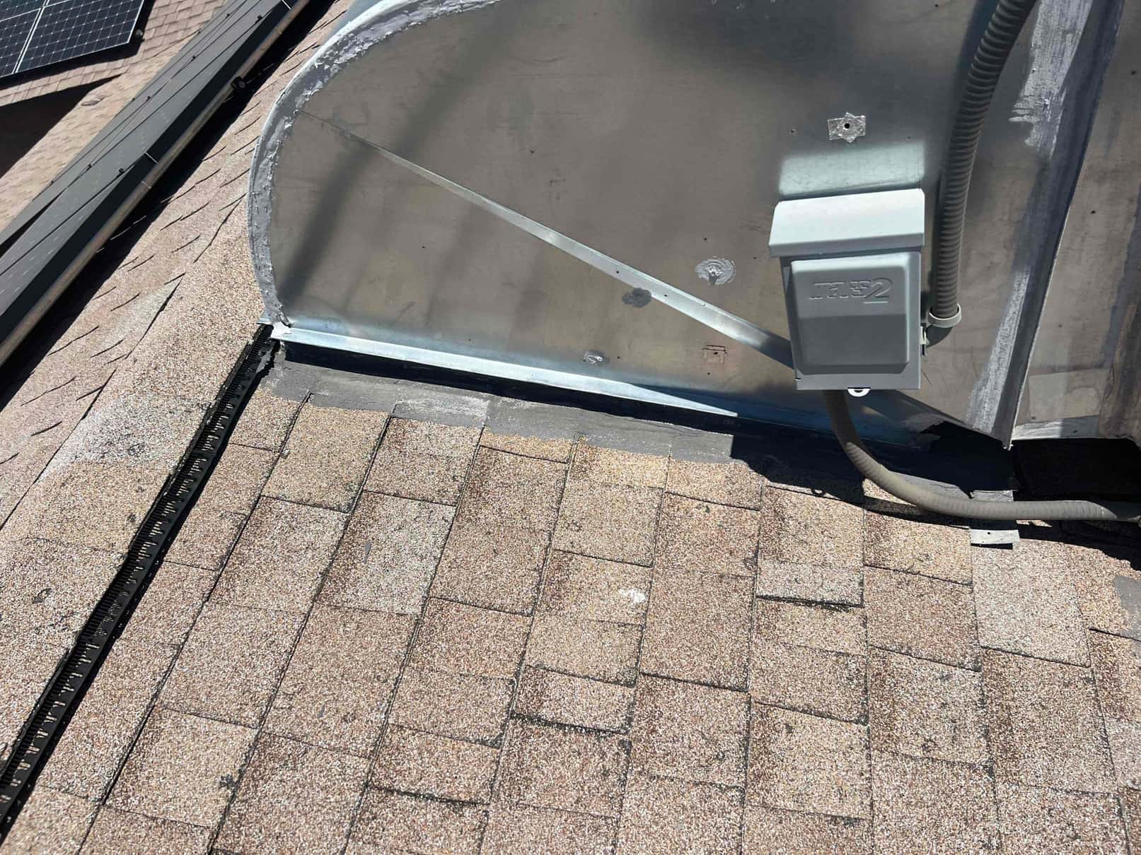 Rooftop metal duct connection with sealed seams, roof curb flashing, and a weatherproof electrical disconnect with flexible conduit.