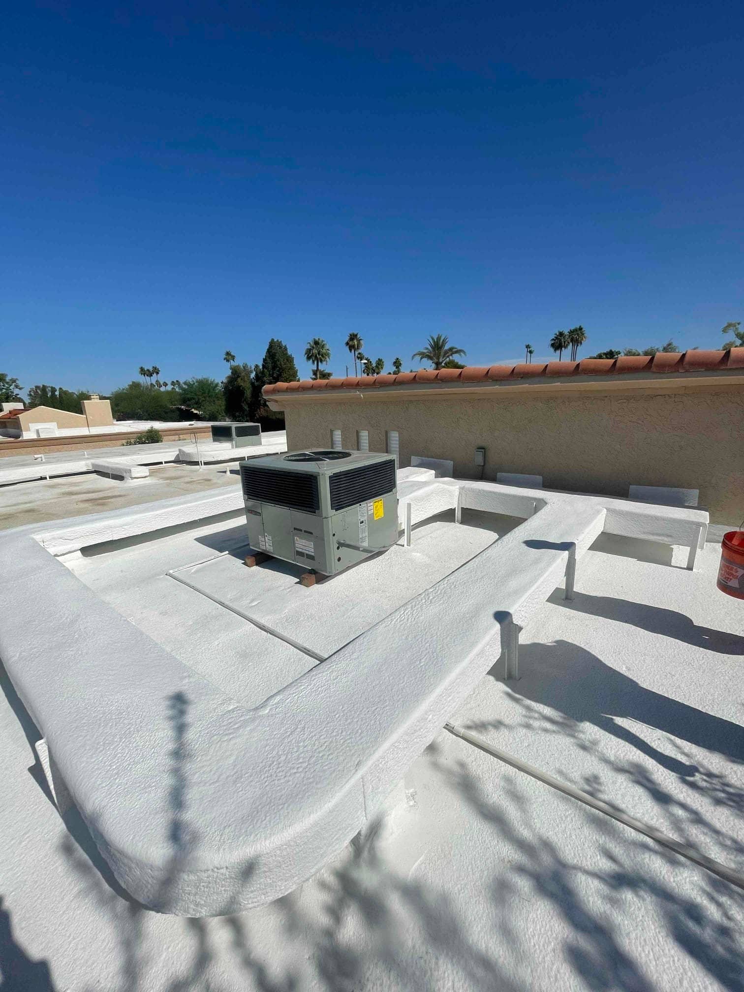 Rooftop package HVAC unit set on supports with sealed roof curb and painted roof surface under clear sky.