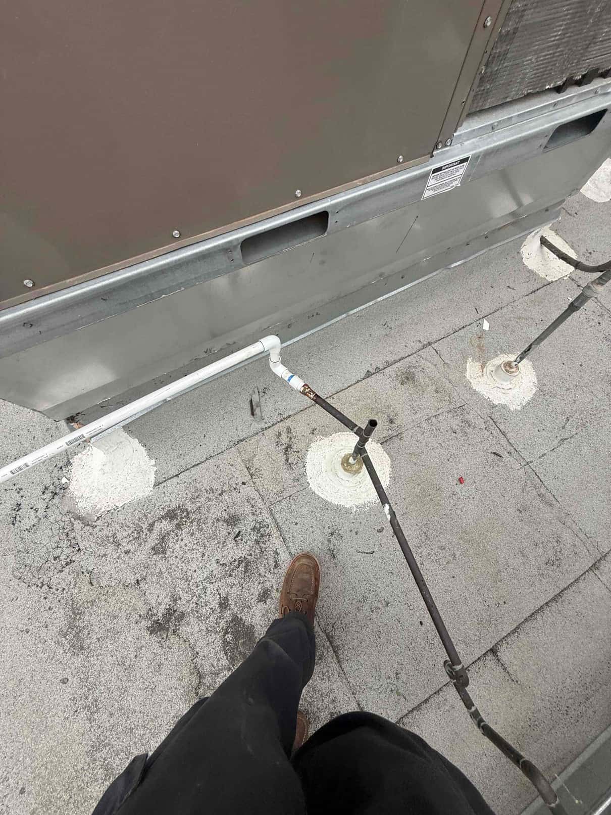 Rooftop package unit curb with new PVC condensate drain and sealed roof penetrations visible during installation.