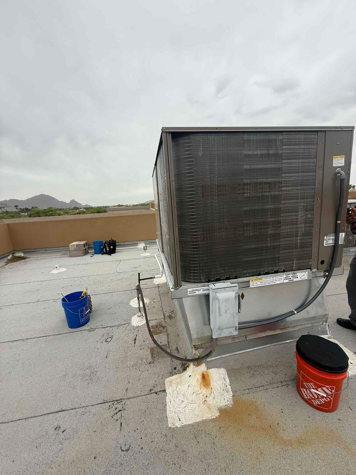 Rooftop package unit set and connected on a flat roof, with electrical conduit and condensate drain routing visible.