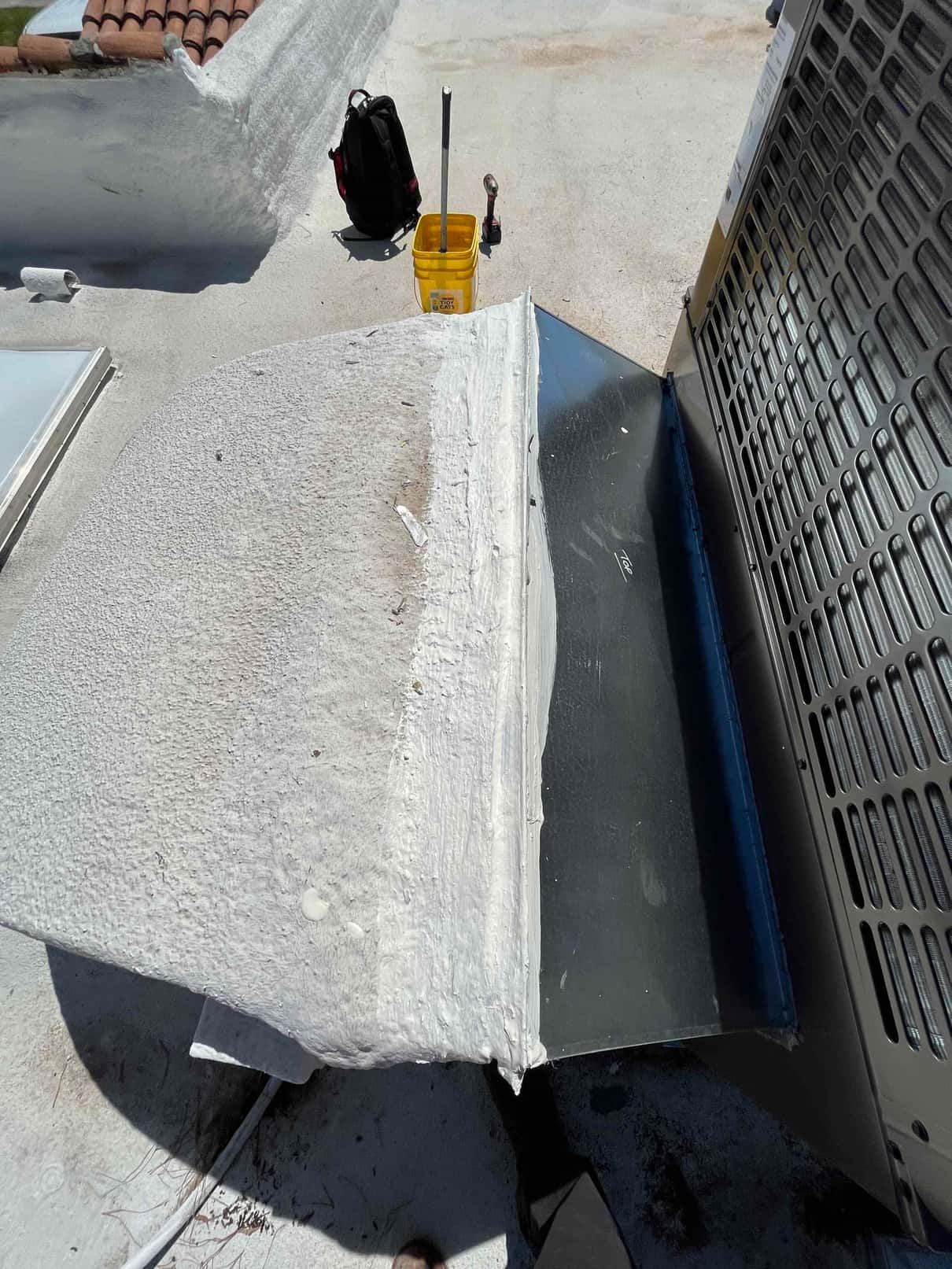 Rooftop package unit set with new sheet metal curb adapter and sealed roof curb transition, tools and bucket nearby.