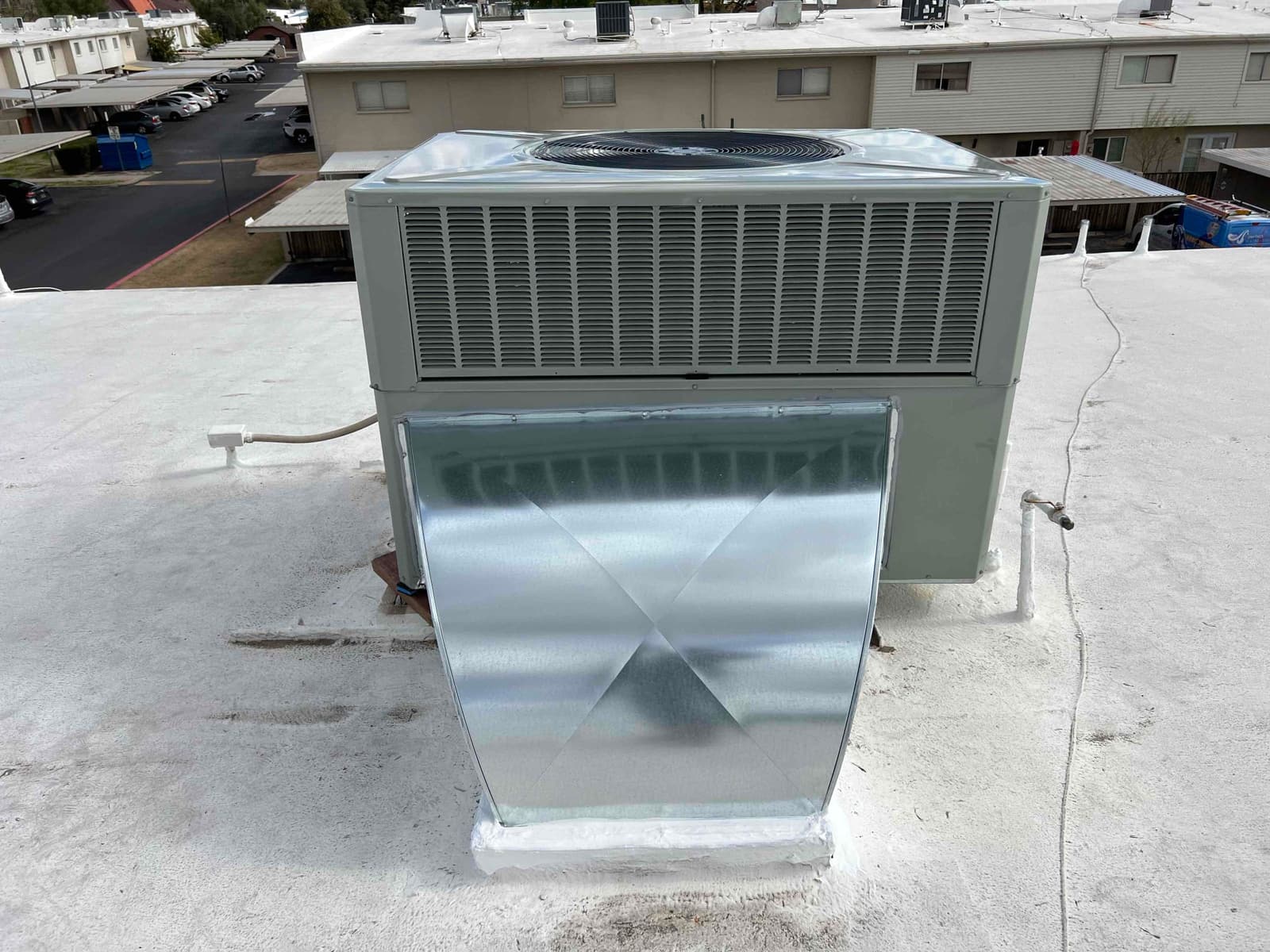 Rooftop packaged heat pump set on a sealed curb with newly fabricated sheet metal duct connection and weatherproofed penetrations.