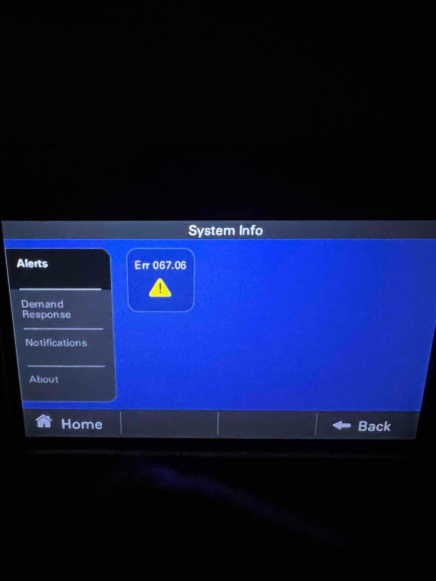 Thermostat touchscreen displays System Info page with an alert icon and code Err 067.06.