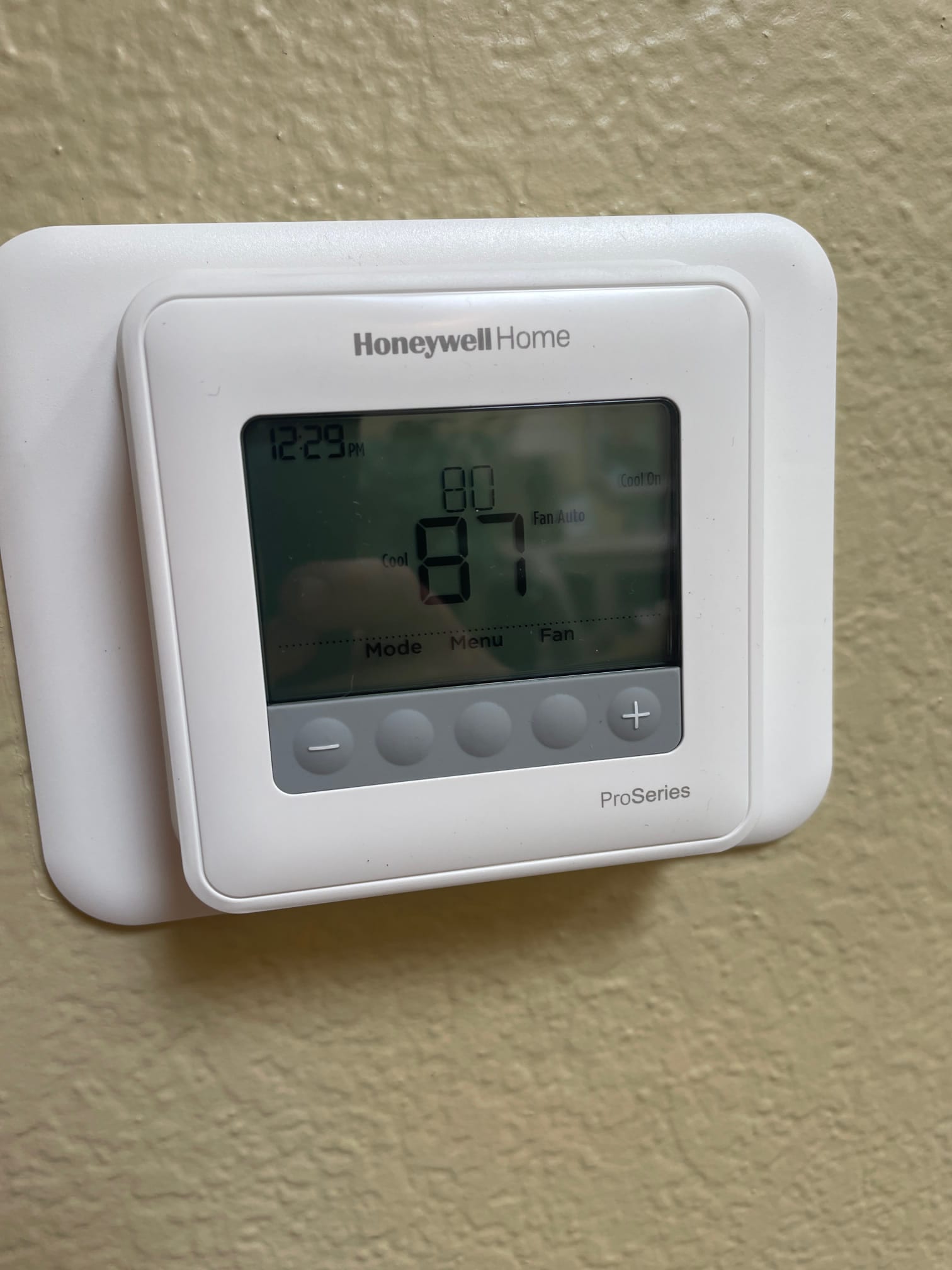 Wall-mounted digital thermostat display shows room temperature 87 with setpoint 80 and fan set to Auto.