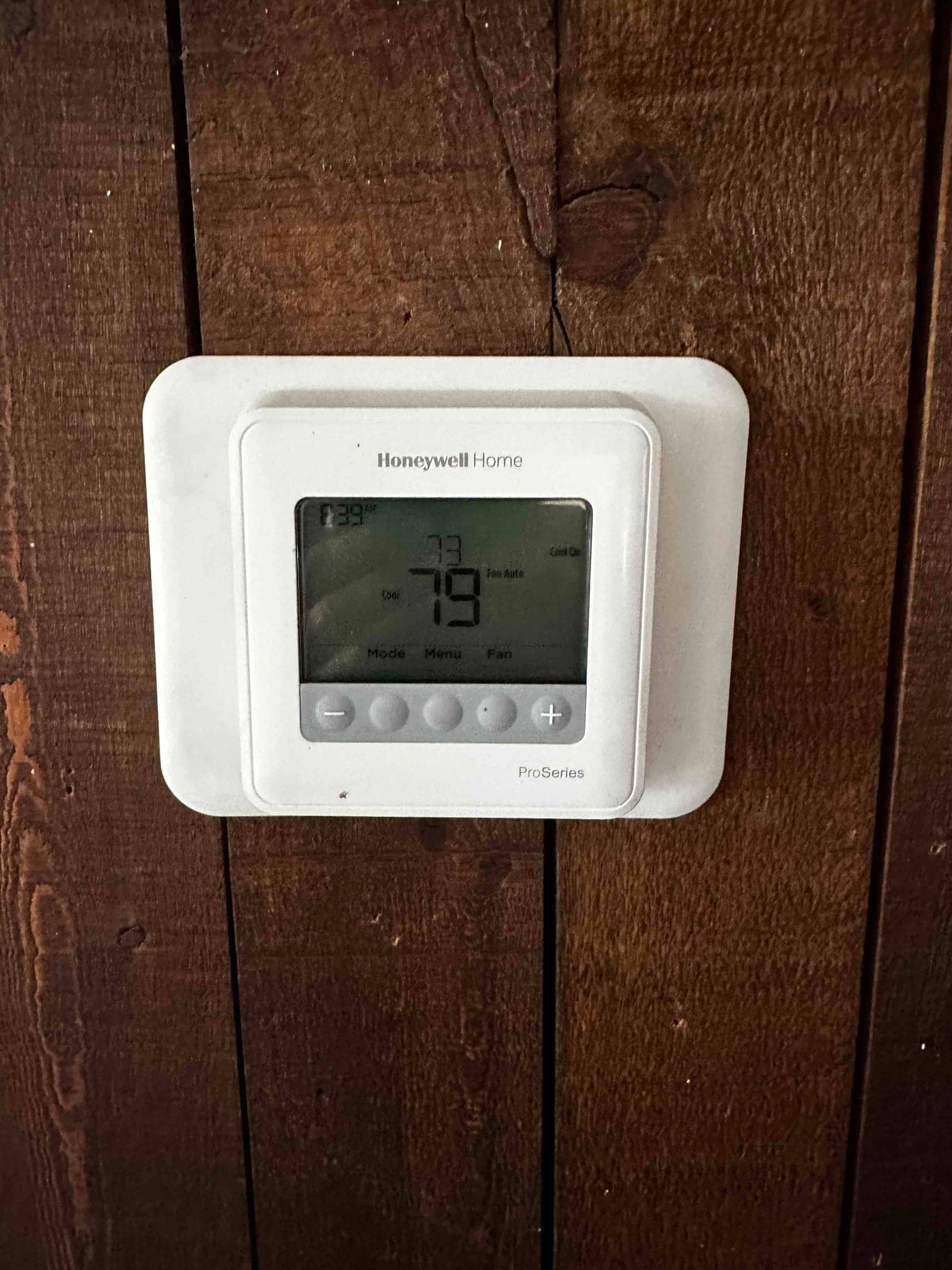 Wall-mounted digital thermostat installed and powered on, displaying current room temperature and cooling mode settings.