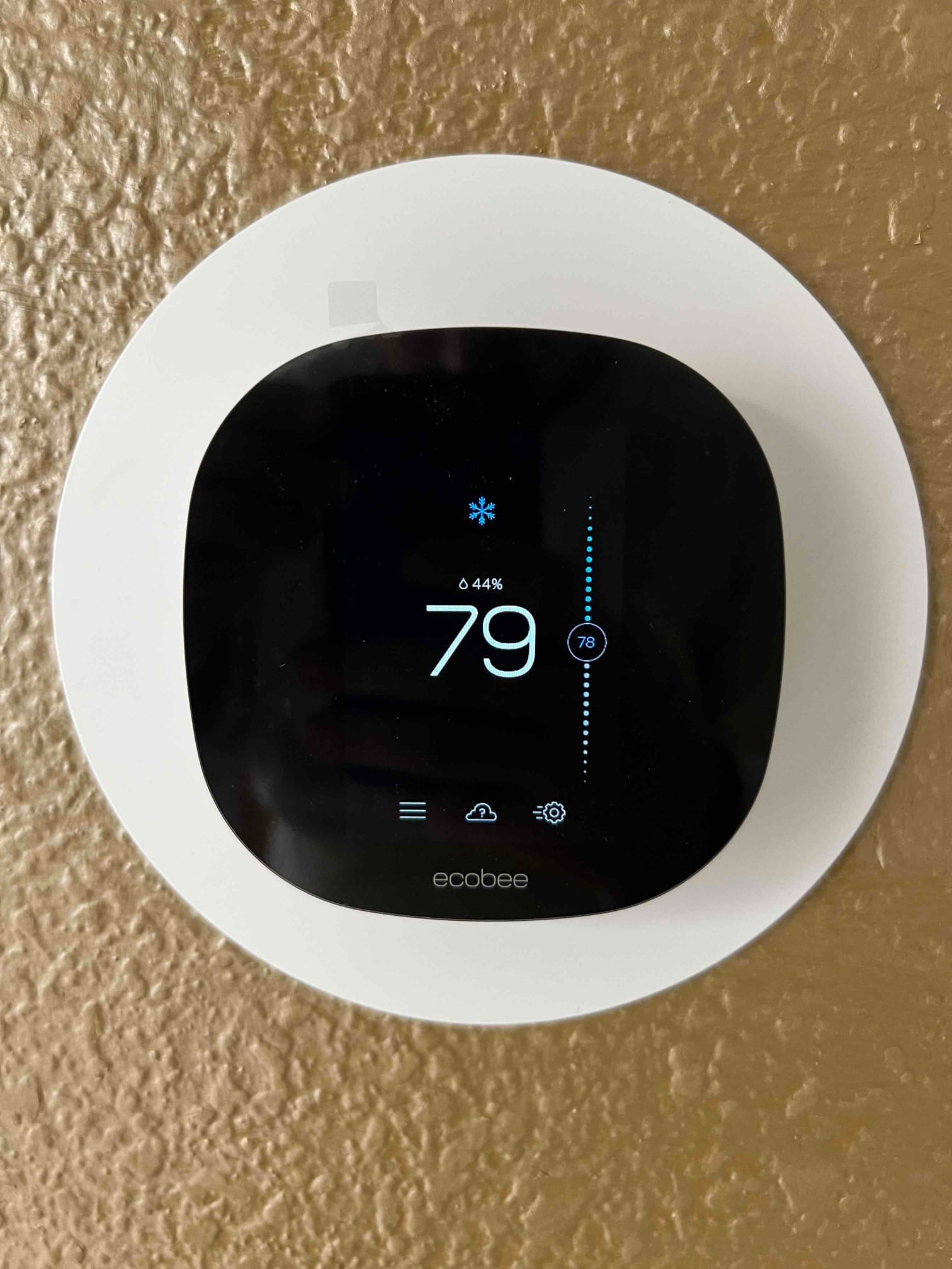 Wall-mounted smart thermostat displaying 79 degrees with cooling mode active and humidity at 44 percent.