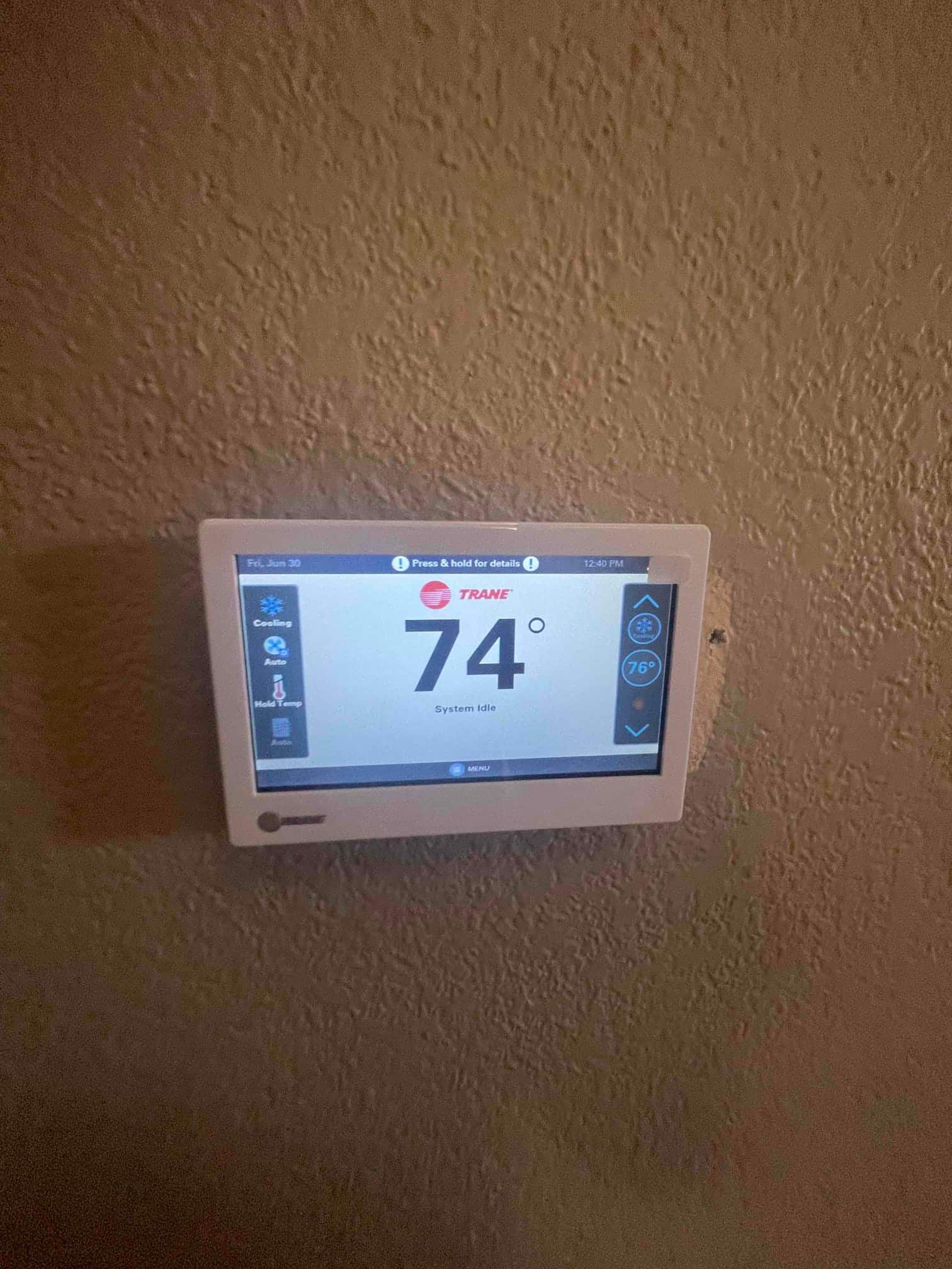 Wall-mounted thermostat displays indoor temperature of 74 degrees with the cooling system shown as idle.