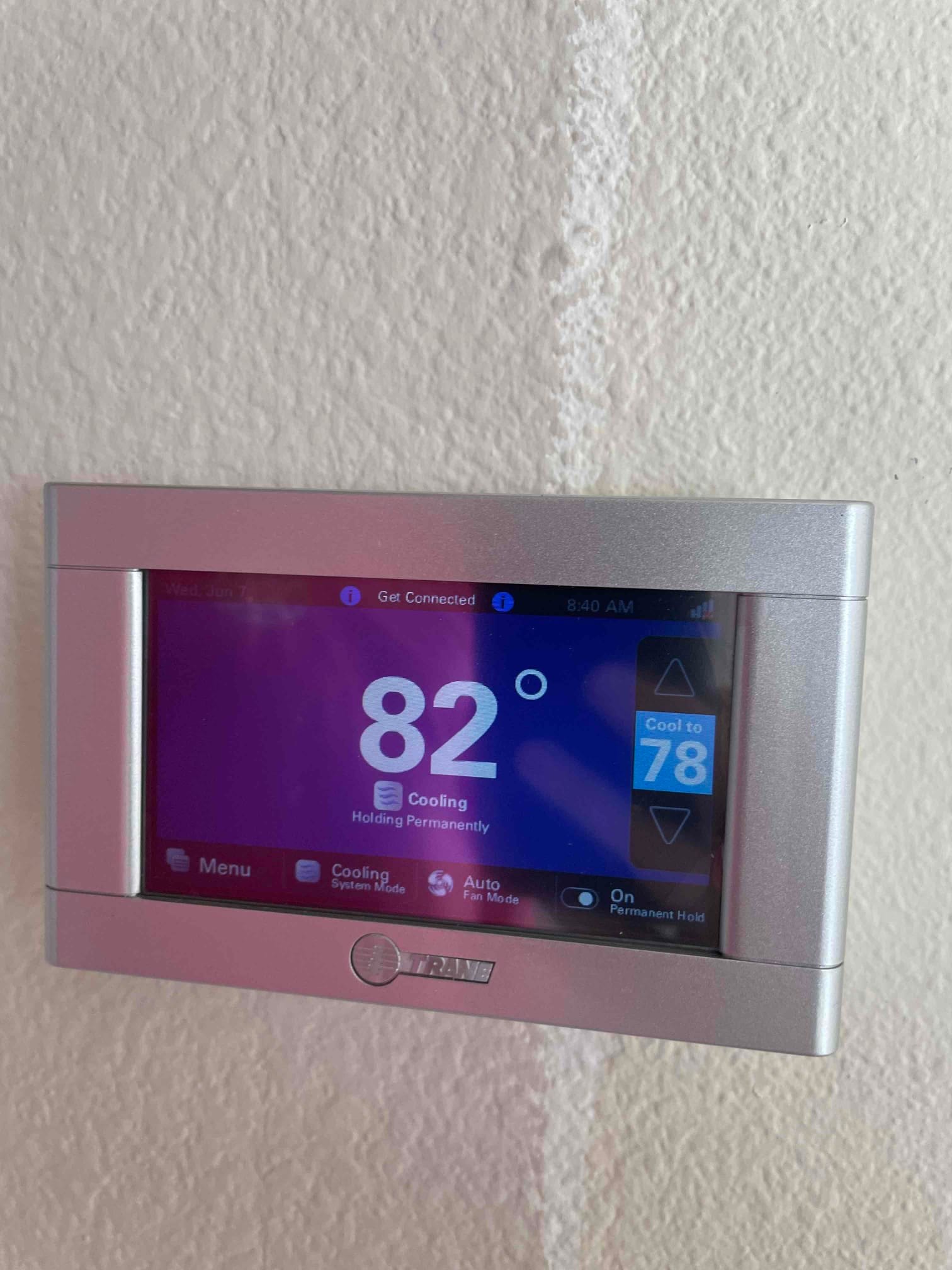 Wall-mounted thermostat displays indoor temperature at 82 degrees with cooling mode active and setpoint of 78.