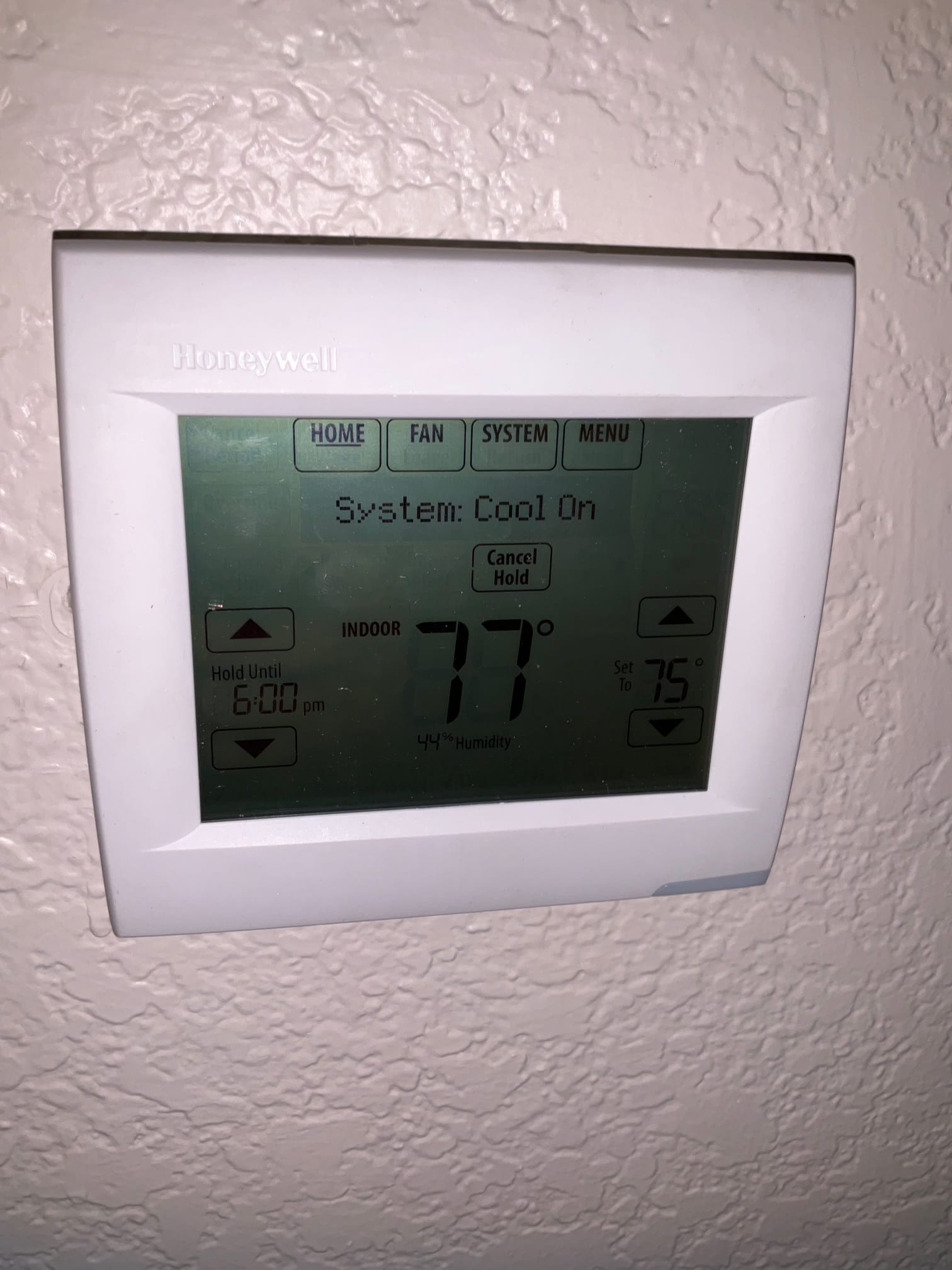 Wall-mounted thermostat displays System Cool On with indoor temperature at 77 degrees and 44% humidity during commissioning.