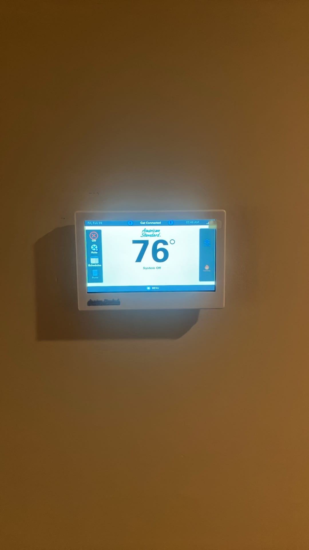 Wall-mounted touchscreen thermostat powered on, displaying indoor temperature of 76 degrees with the system currently off.