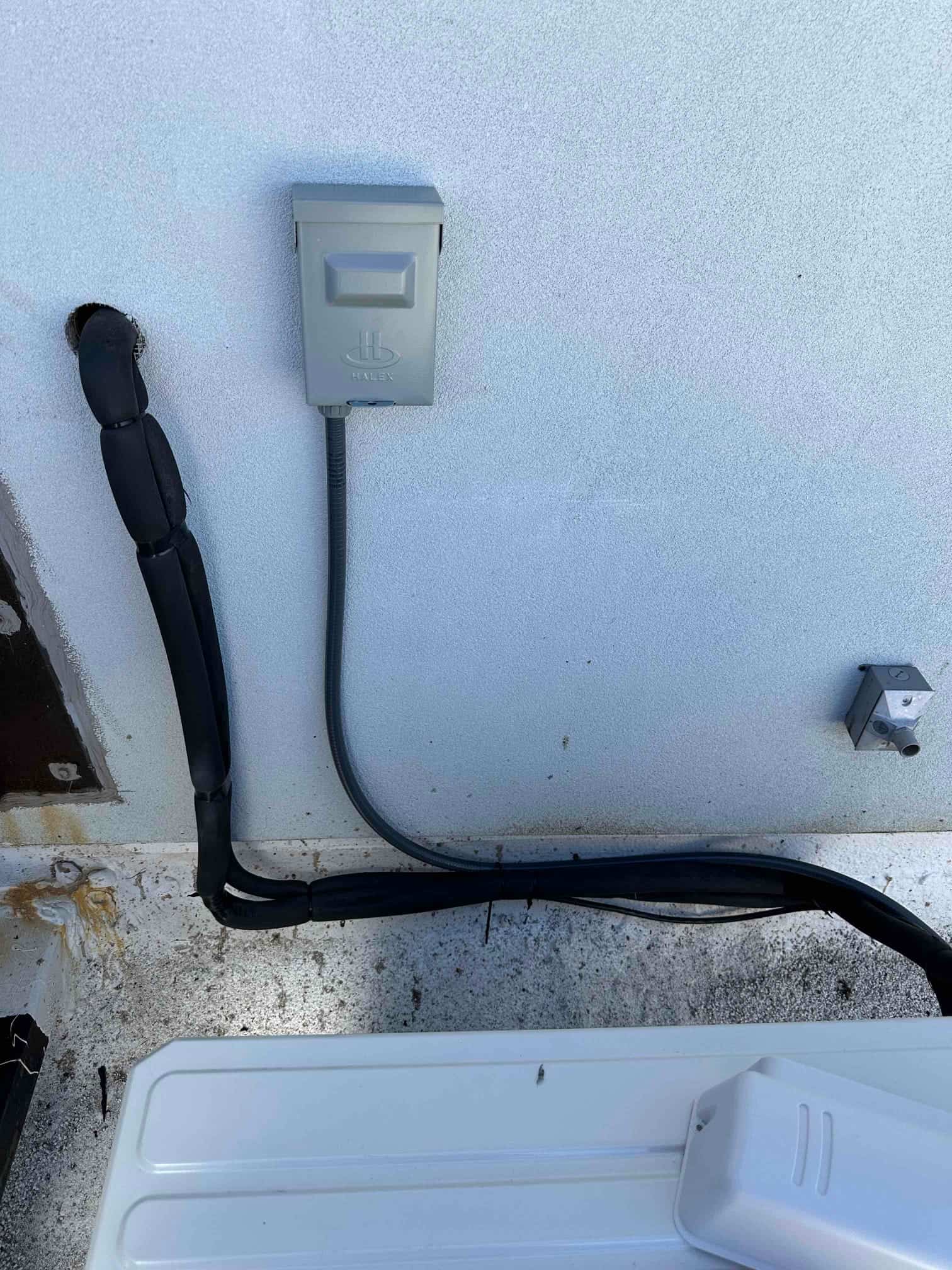 Weatherproof disconnect and flexible conduit installed beside insulated refrigerant lines for the new mini-split outdoor unit.