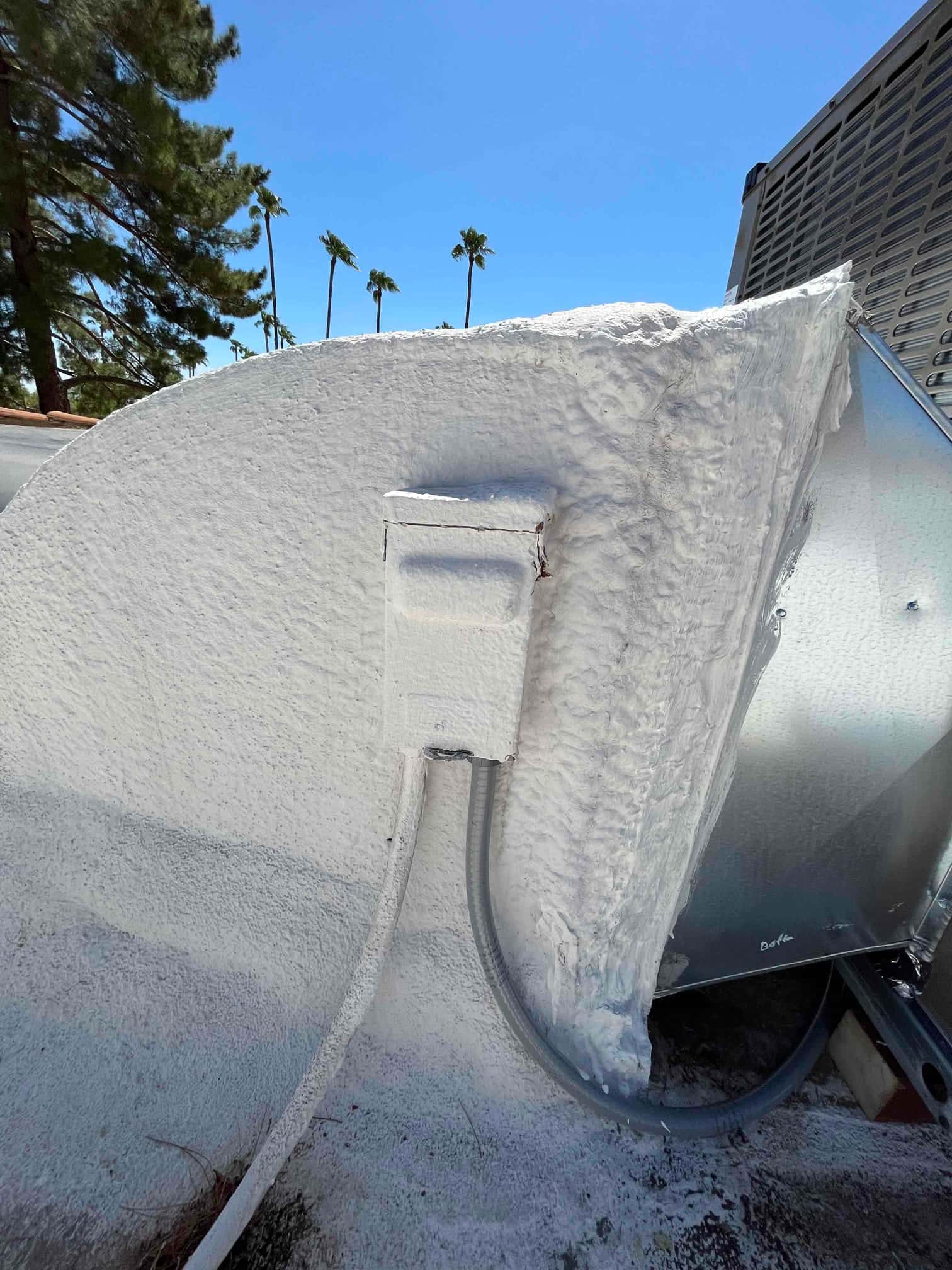 Weatherproof electrical disconnect and flexible conduit installed beside the rooftop package unit, with sealed roof penetration for protection.