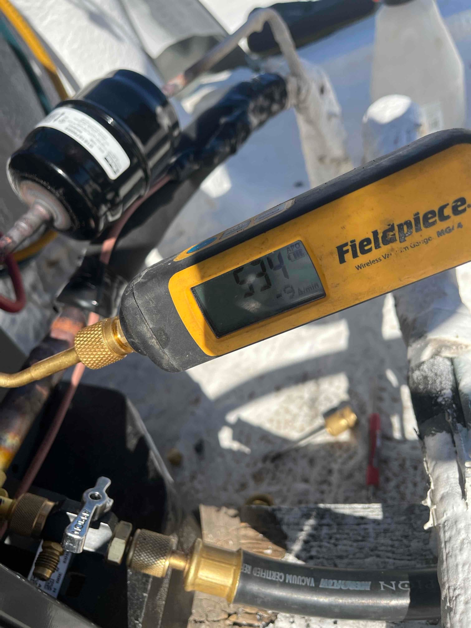 Wireless micron gauge connected to the service port shows 394 microns during system evacuation prior to refrigerant charging.