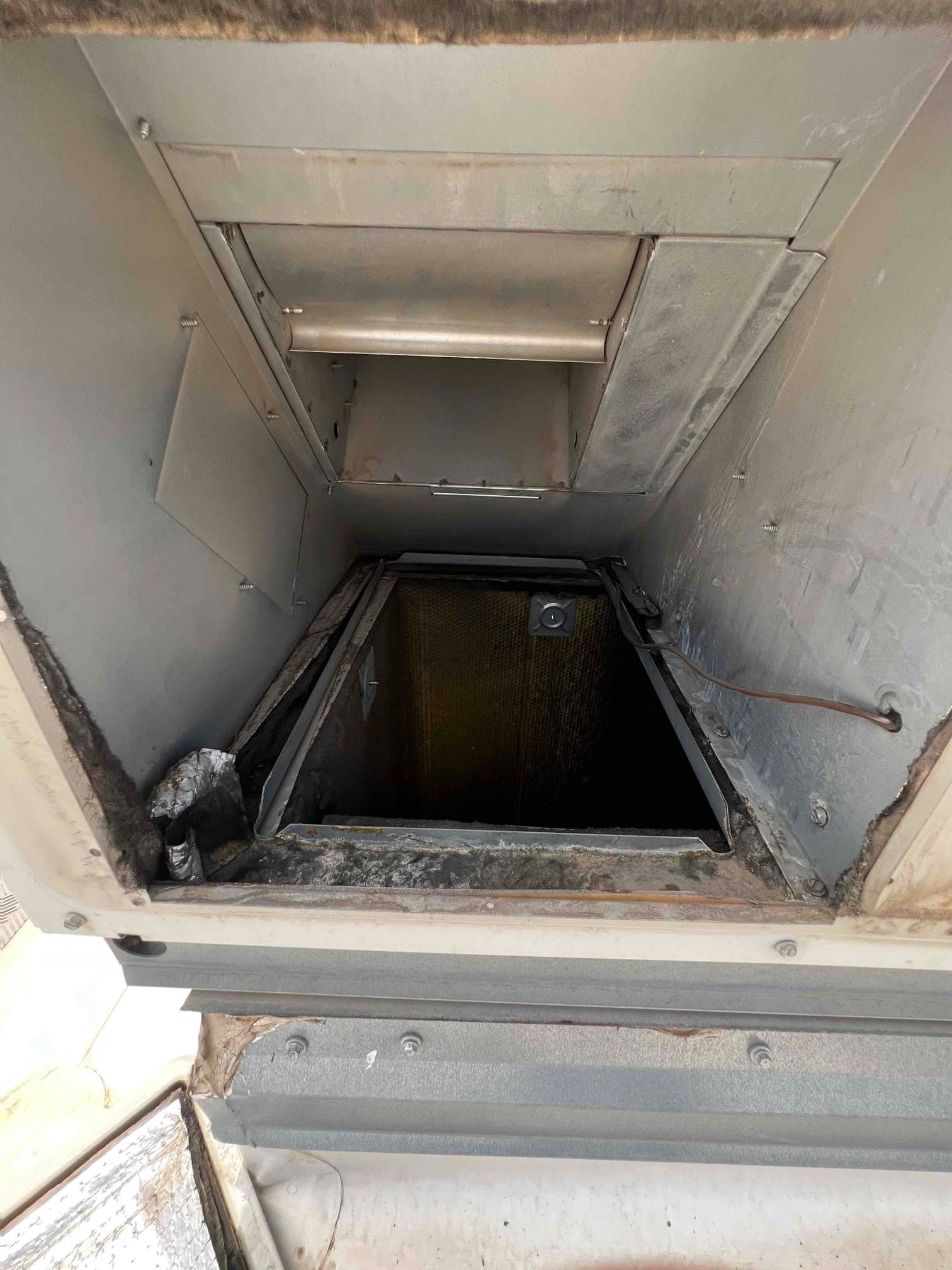 Air handler cabinet interior with evaporator coil and drain line visible, showing open access panel and surrounding insulation.