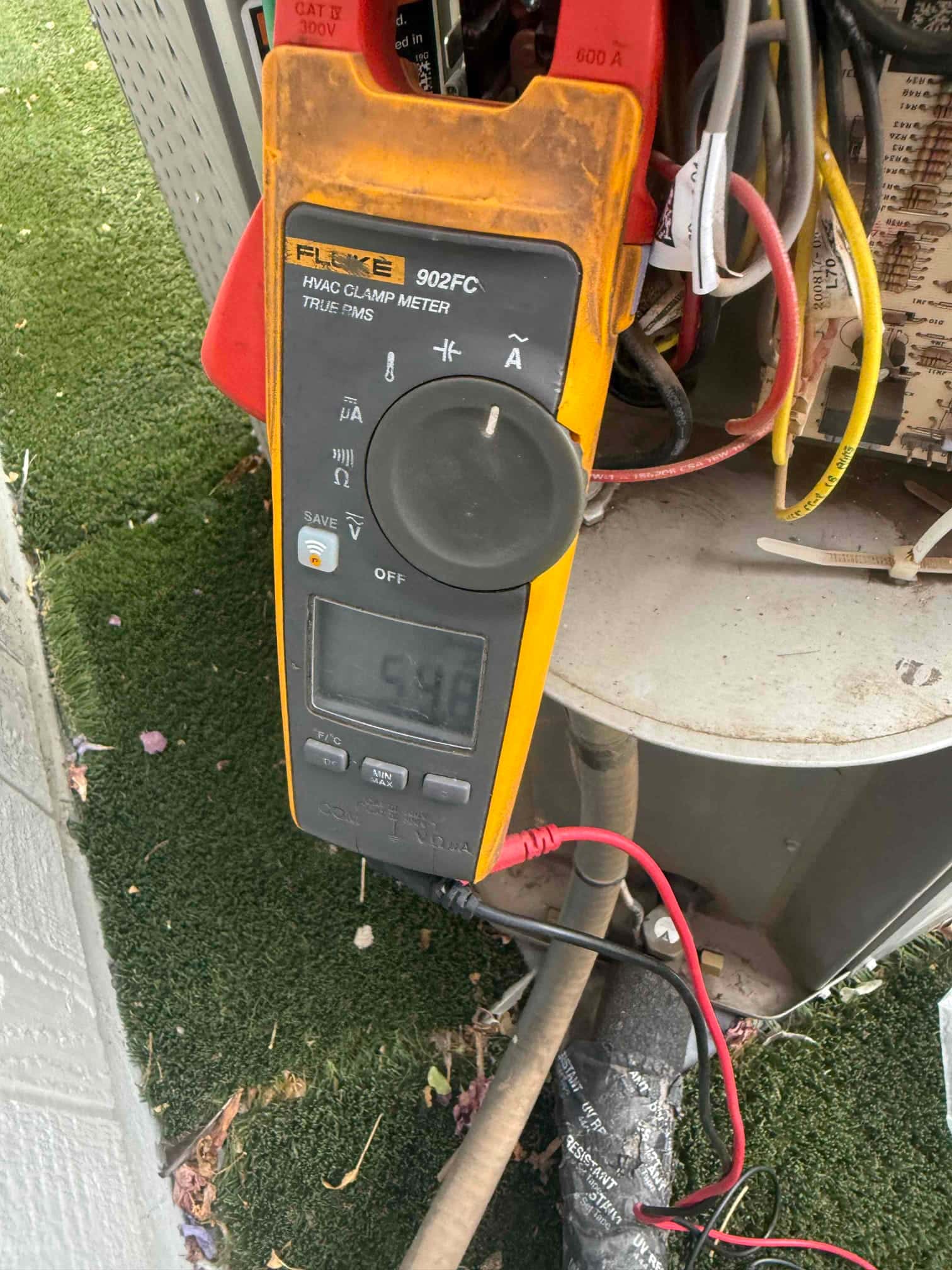 Clamp meter shows 5.8 A on a connected lead at the outdoor condenser wiring compartment.