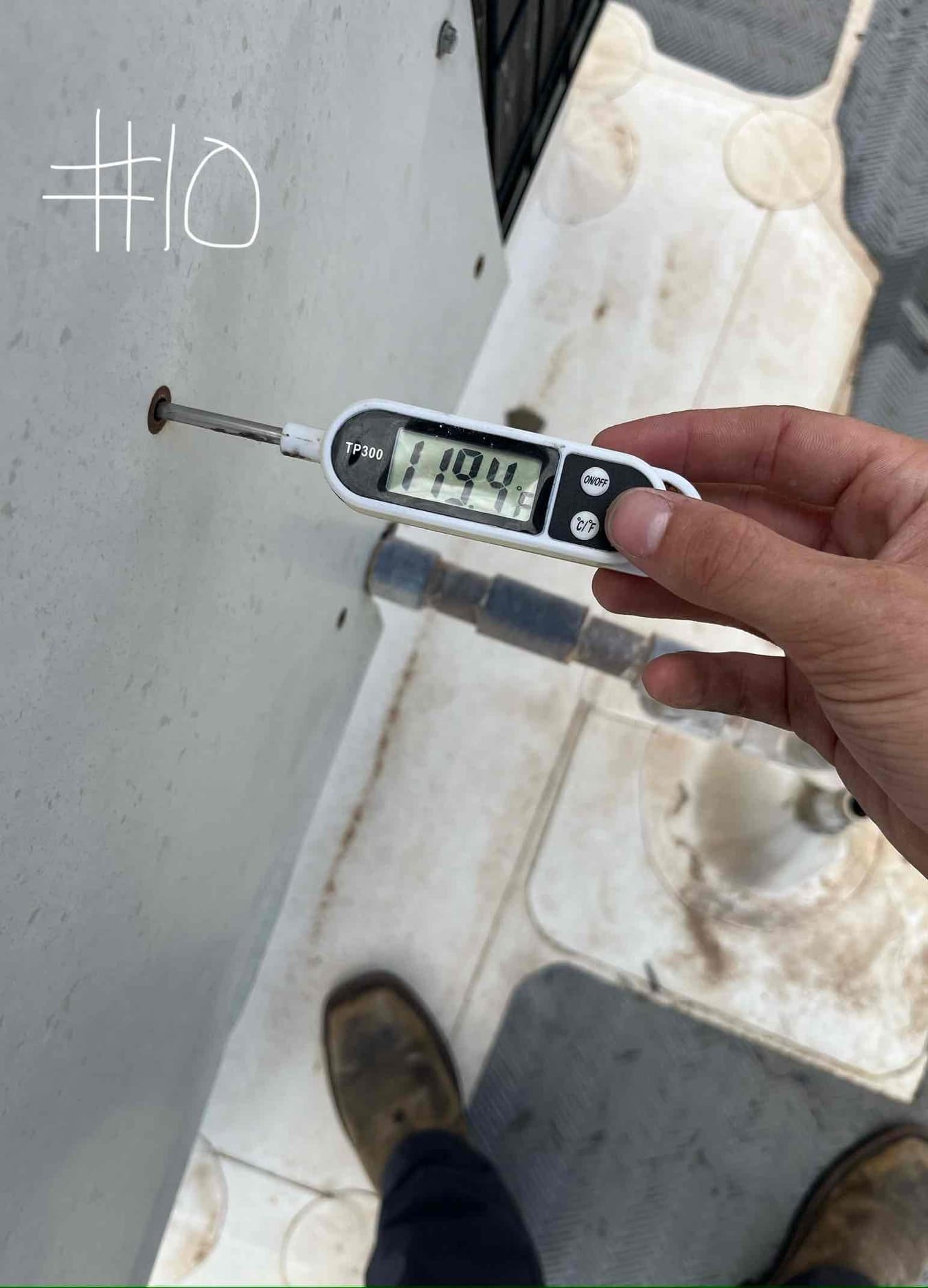 Digital thermometer measures 119.4 °F on the metal surface of the outdoor air conditioning unit panel.