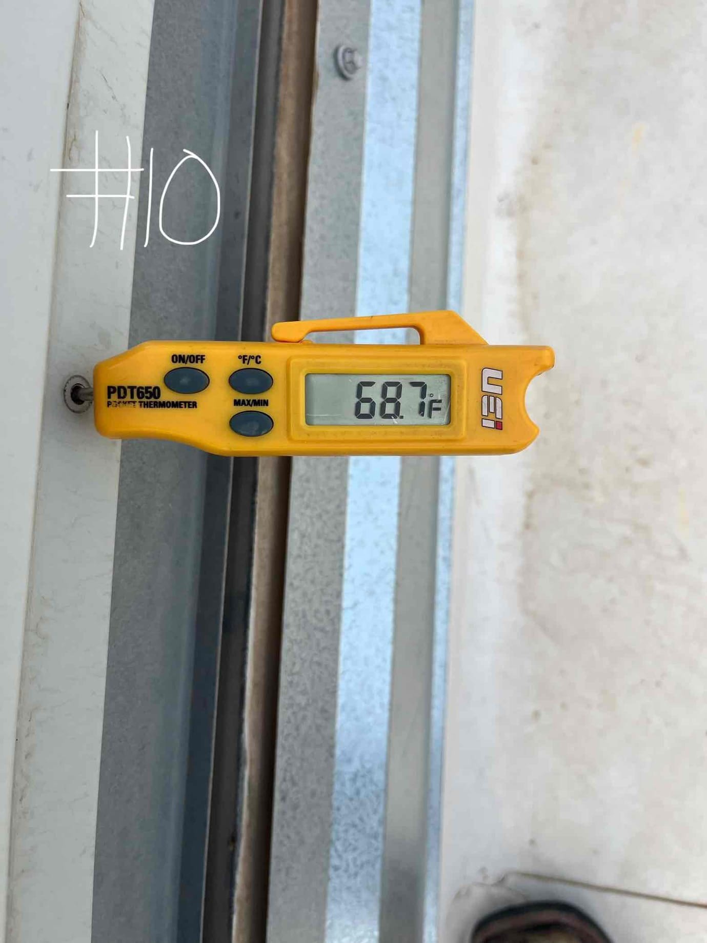 Digital thermometer shows 68.7 °F at the probe tip during air conditioning repair diagnostics.